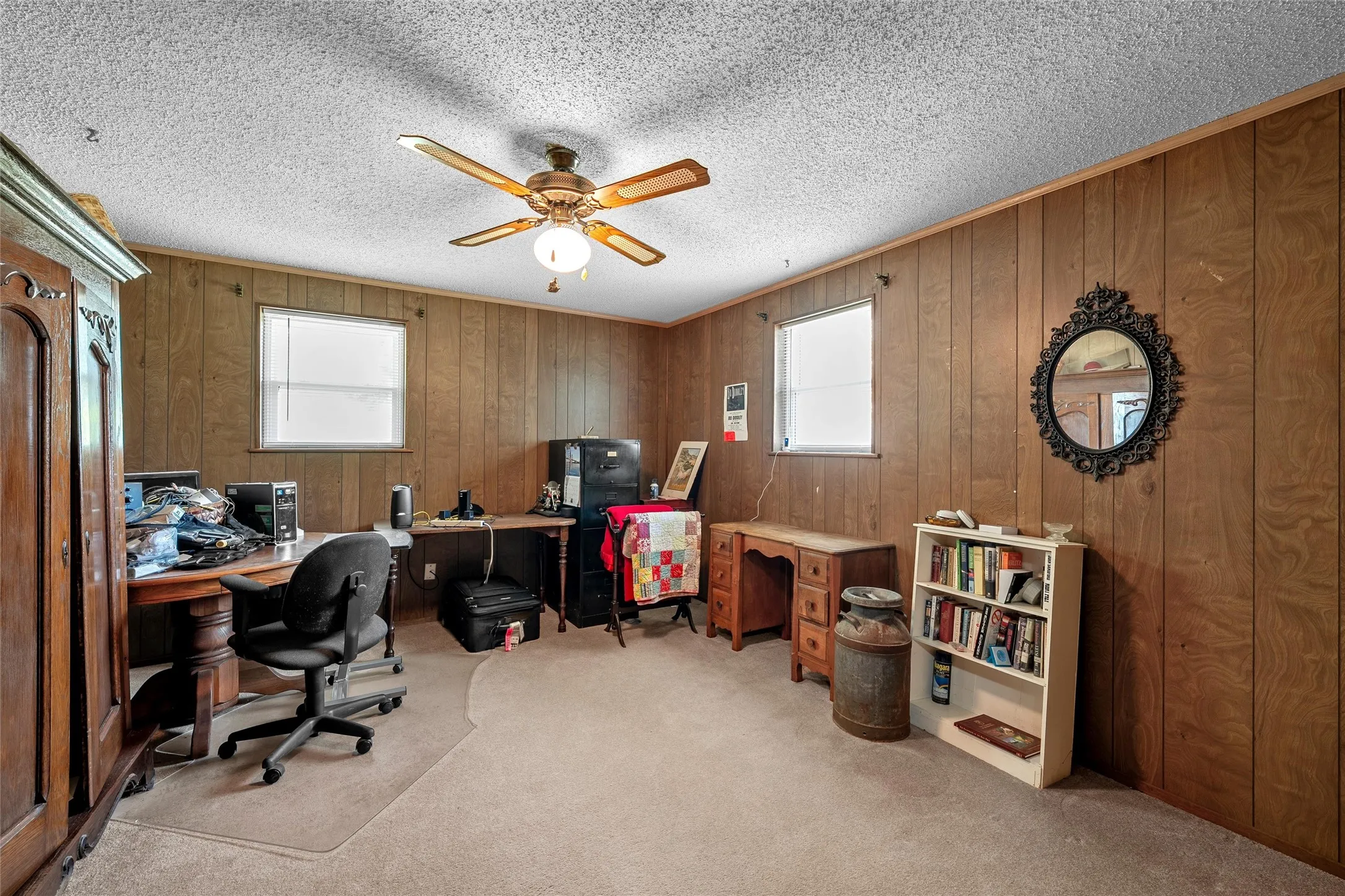 Room featuring wood paneling, a textured ceiling, two windows, recessed lighting, and a ceiling fan with integrated lighting