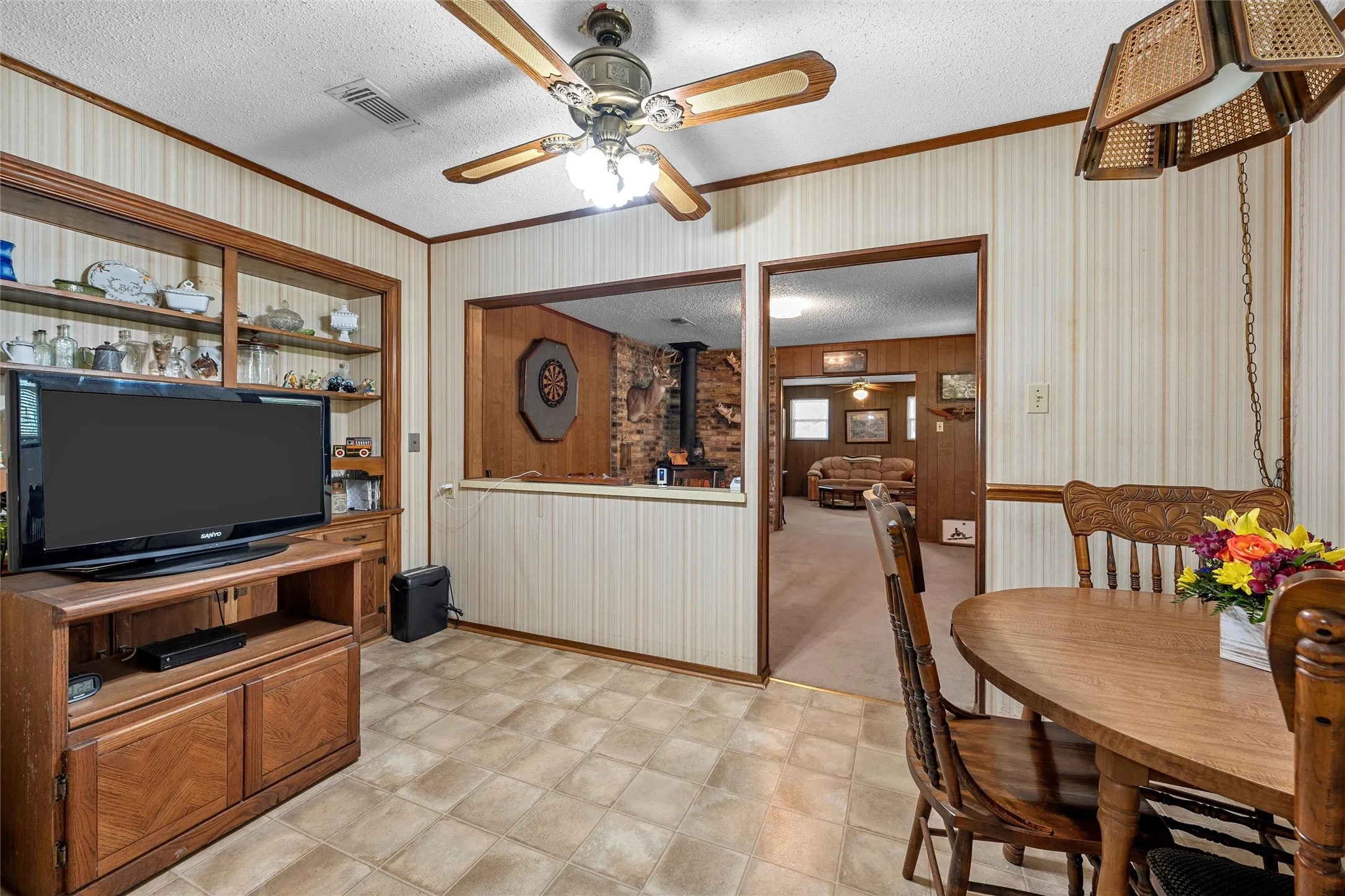 Interior space featuring patterned wallpaper with wood trim, a built-in display cabinet, and tiled flooring
