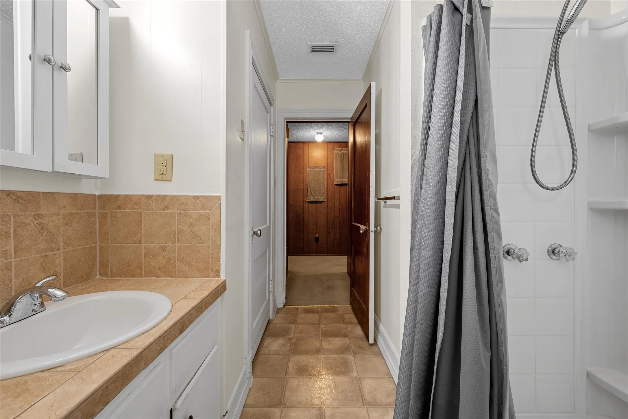 Bathroom featuring a white vanity with an integrated sink, tiled countertop, and matching tiled backsplash