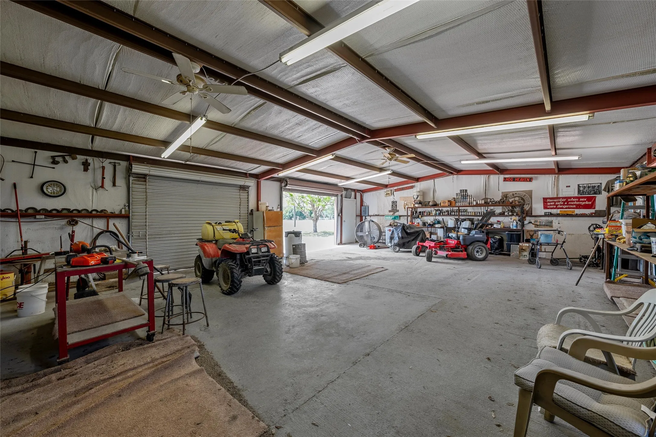 Spacious metal-frame building featuring concrete flooring, exposed beam ceiling, and fluorescent lighting