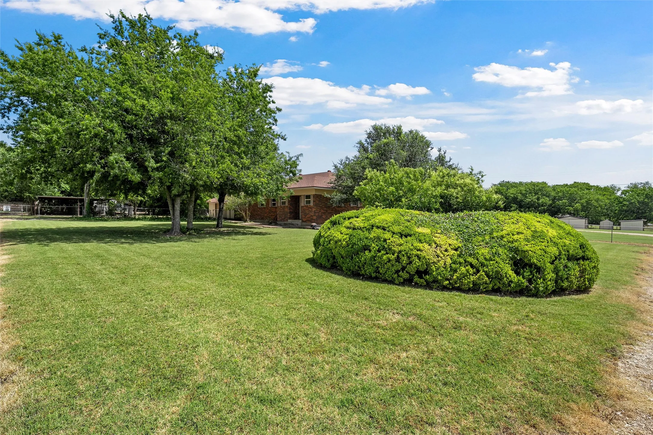 Expansive green lawn with mature trees and sculpted shrubbery