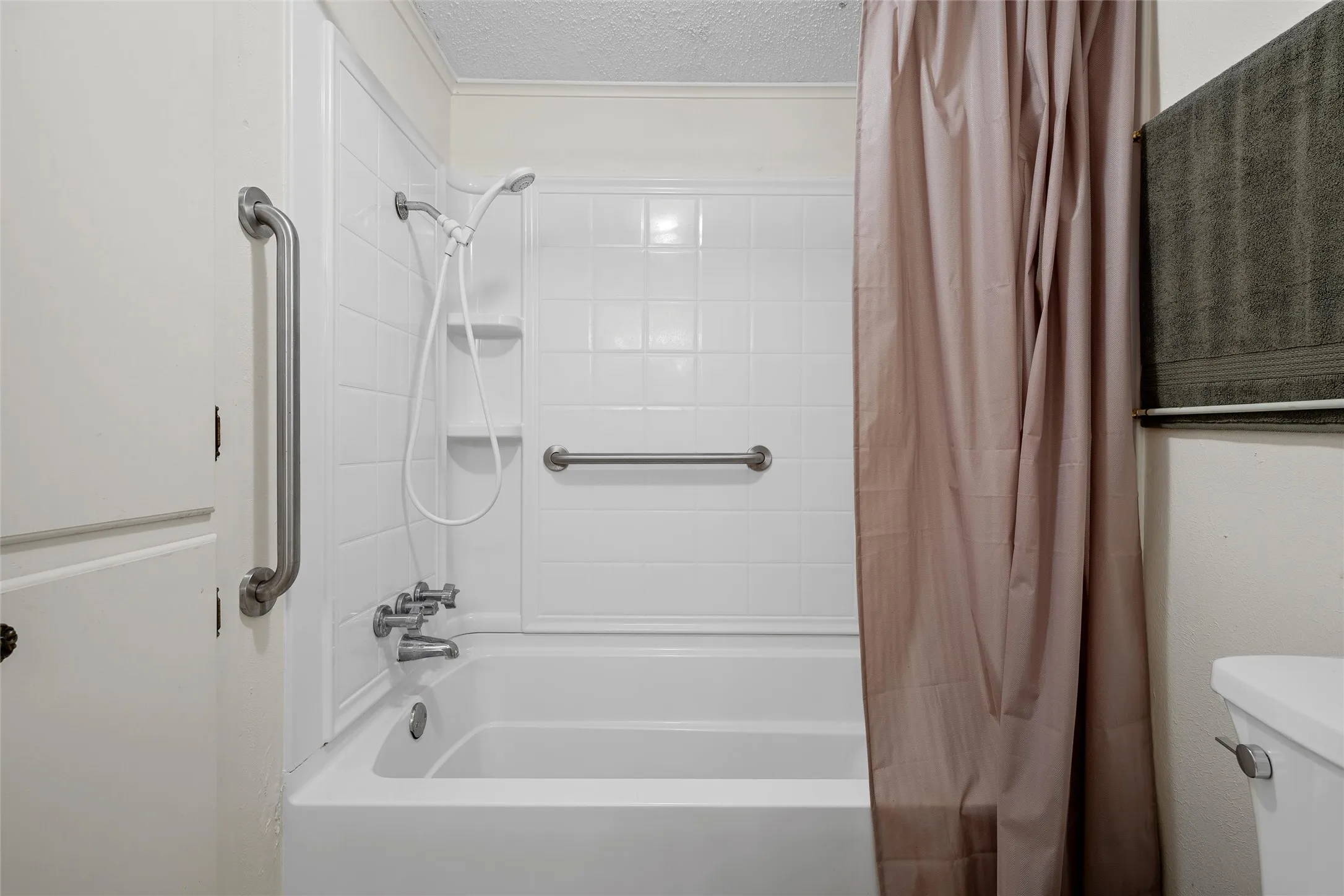 Bathroom featuring a white tub, white tiled surround, and integrated shelving