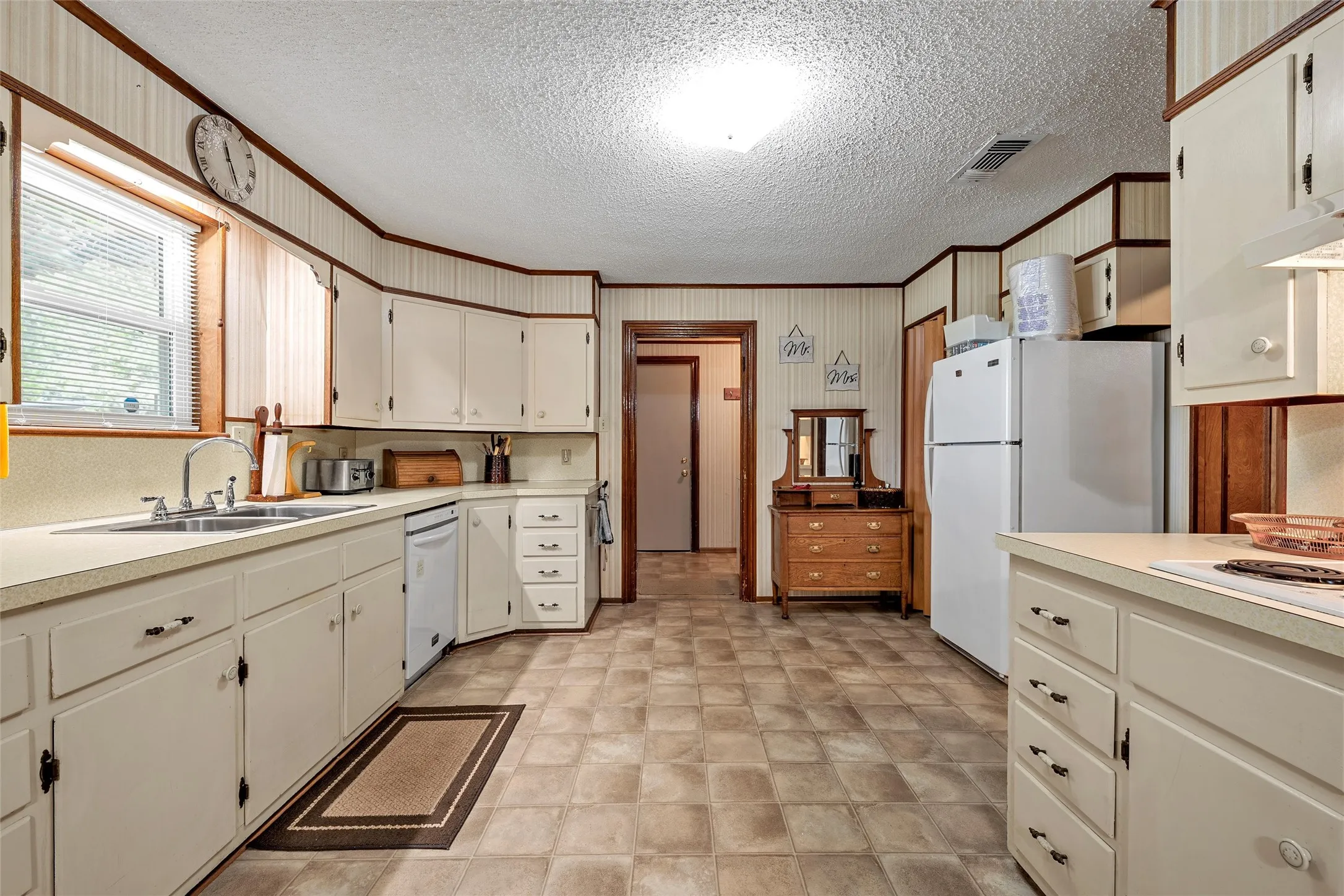 Kitchen featuring ample cabinetry, a double basin sink, and a built-in dishwasher