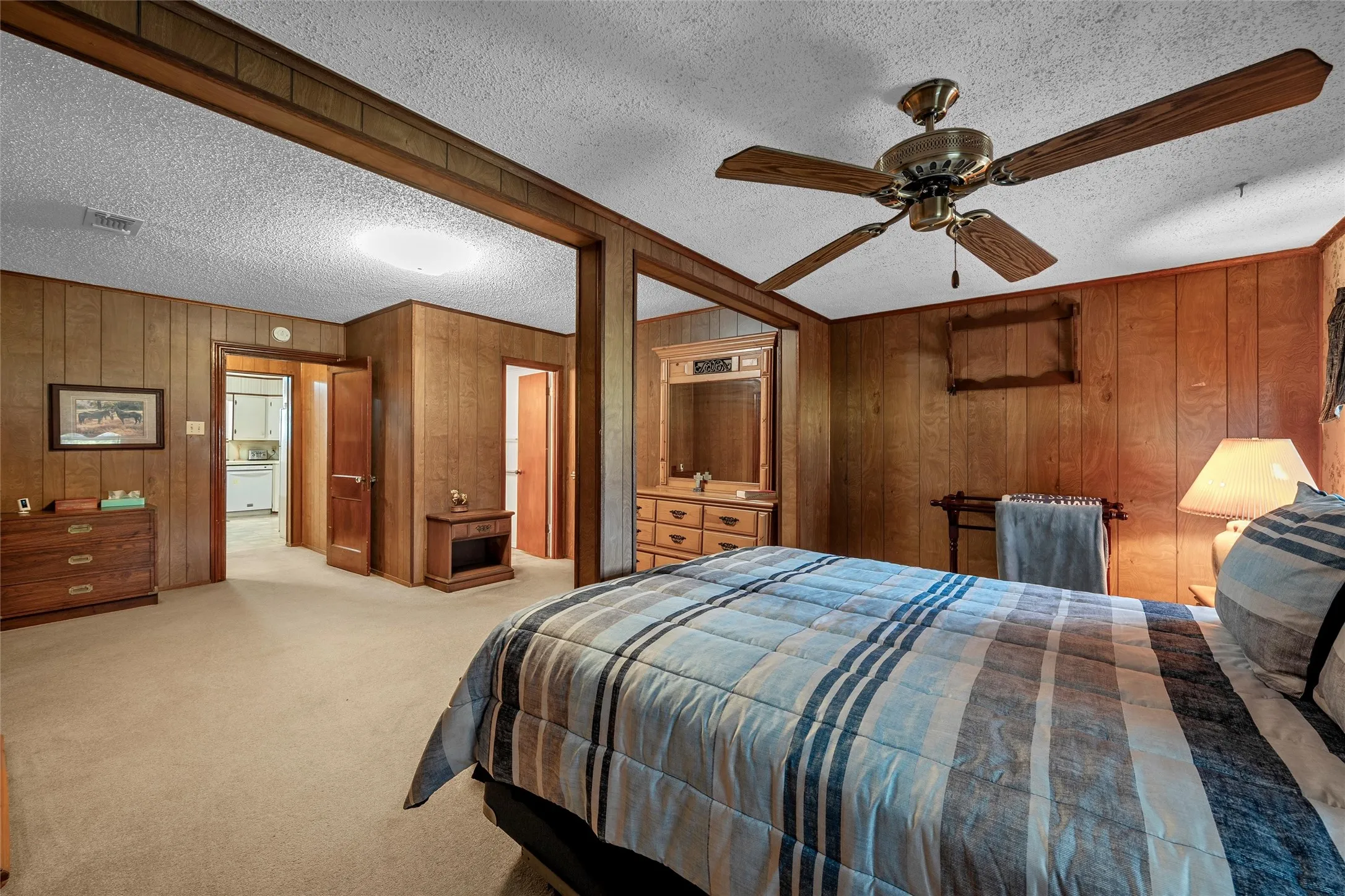 Room featuring wood-paneled walls, carpeted flooring, and a ceiling fan