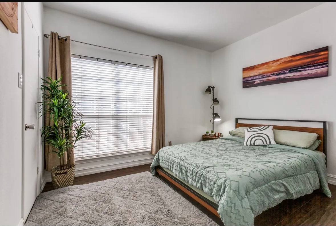 Bedroom with dark wood-style floors and baseboards