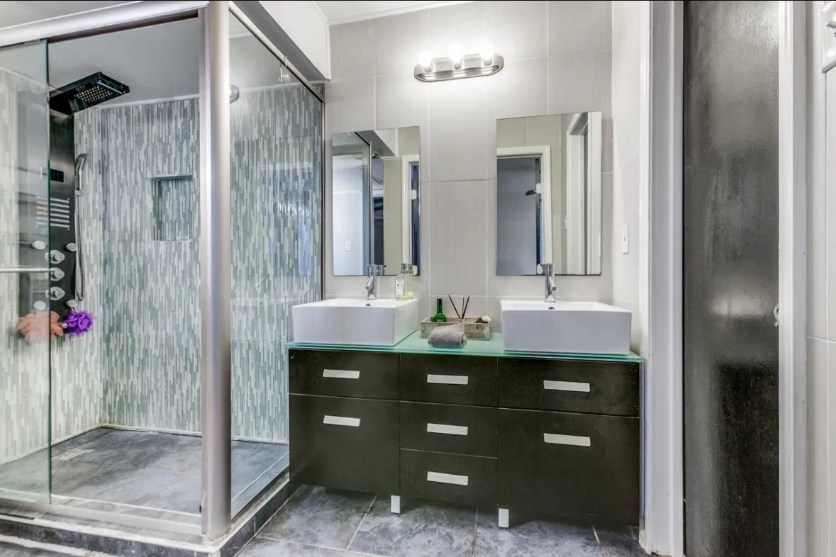 Full bath with a shower stall, double vanity, and tile patterned flooring