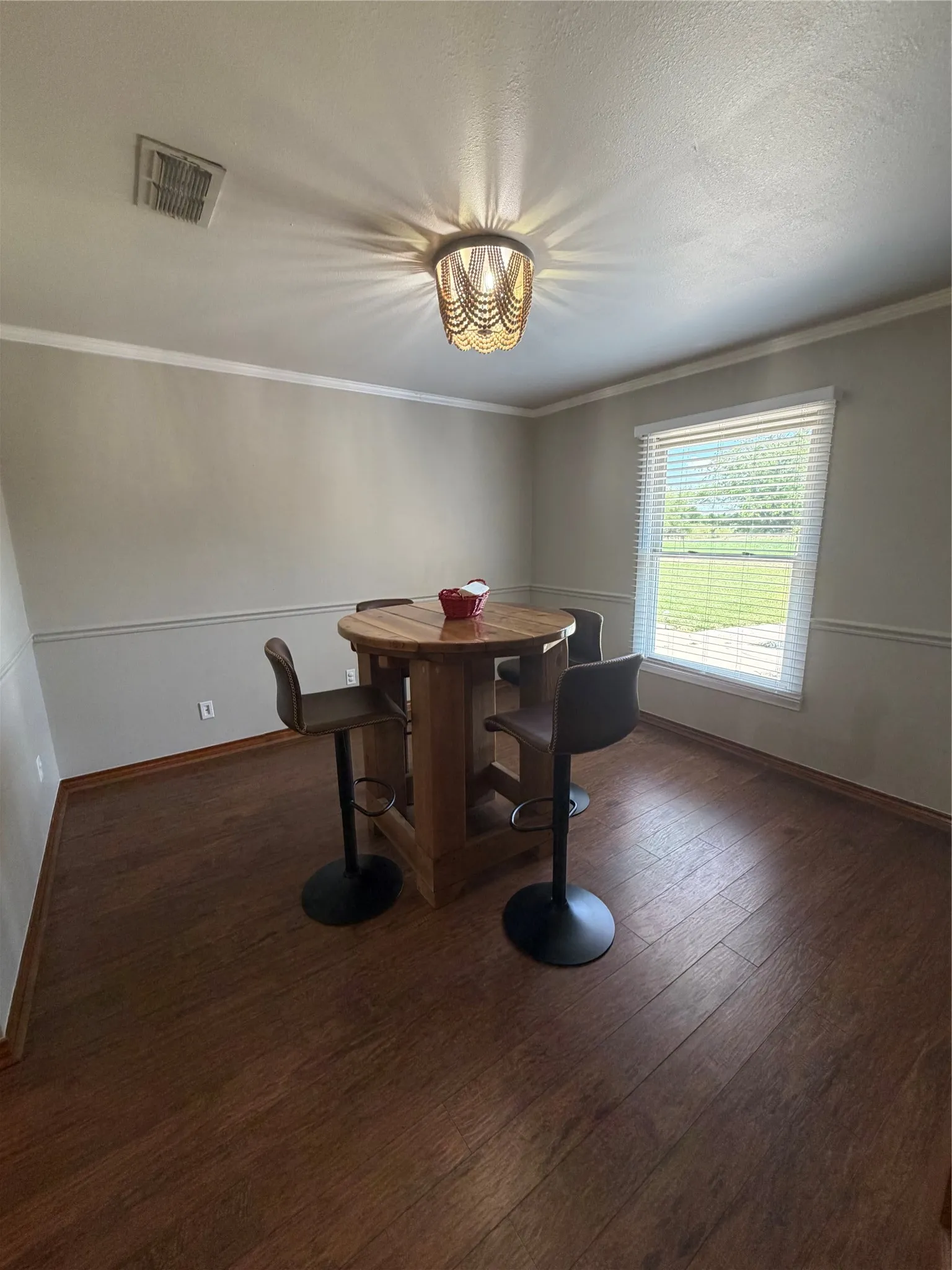 Recessed ceiling light fixture, wood-finish flooring, two-tone wall paint, crown molding, and a window with blinds