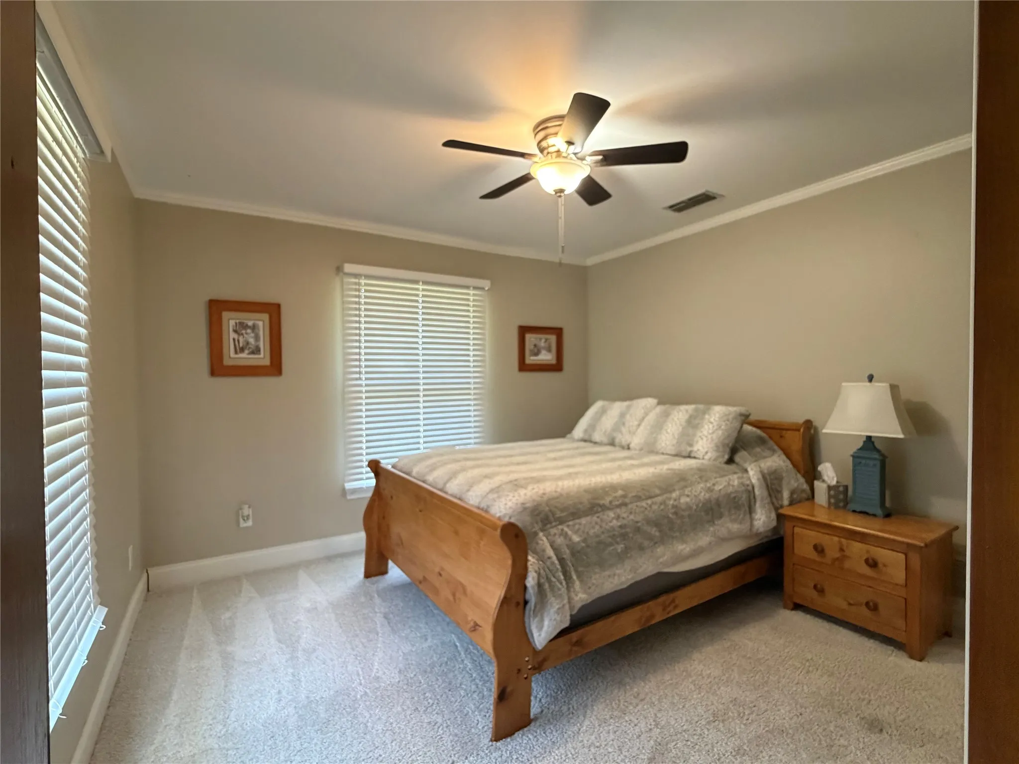 Carpeted room featuring a ceiling fan with integrated lighting, crown molding, and two windows with​​‌​​​​‌​​‌‌​‌‌​​​‌‌​‌​‌​‌​​​‌​​ blinds