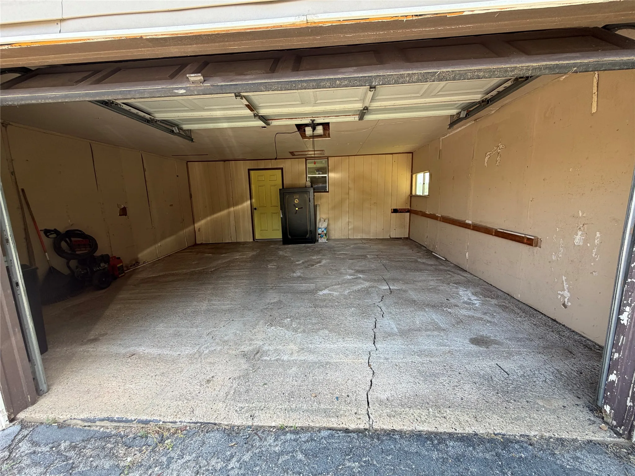 Single-bay garage featuring a concrete floor, a light-colored interior door, and a built-in wall shelf