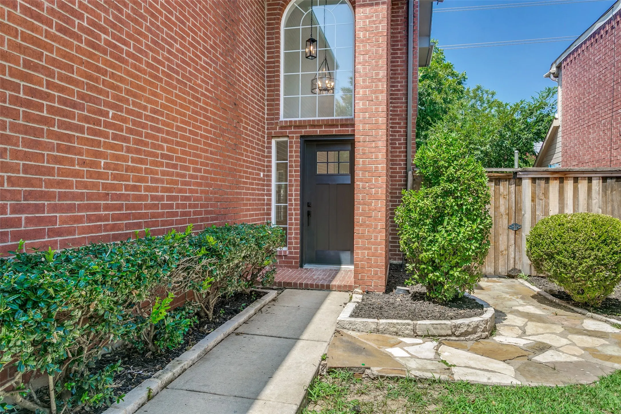 Brick exterior featuring a tall arched window above a paneled entry door