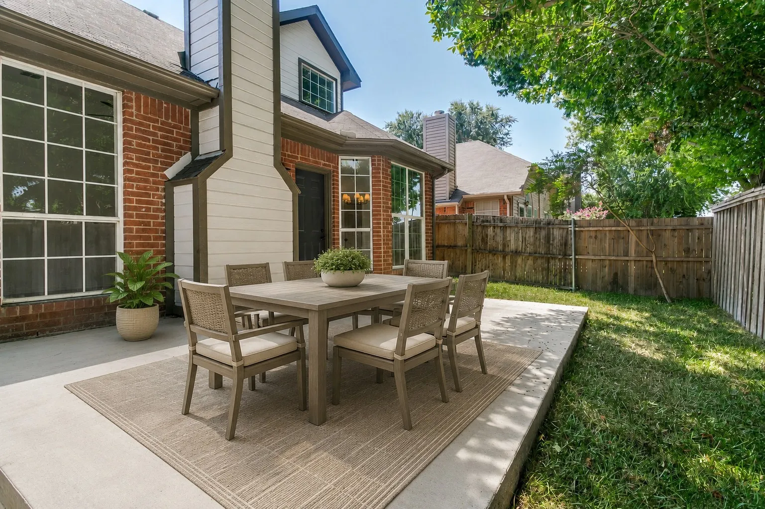 Expansive concrete patio with brick and siding exterior and privacy fencing