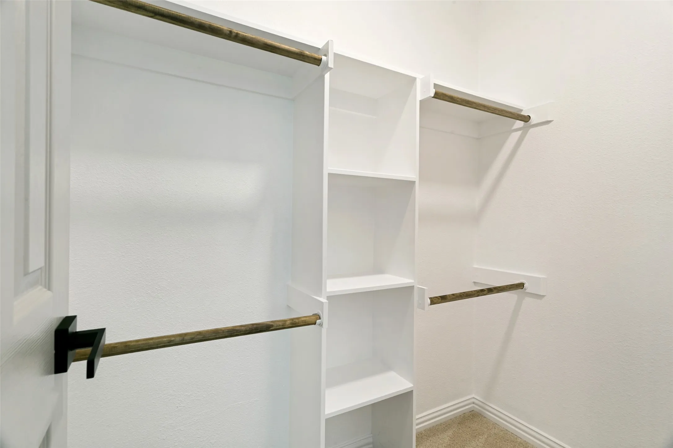 Walk-in closet featuring built-in shelving, multiple hanging rods, and neutral carpet flooring