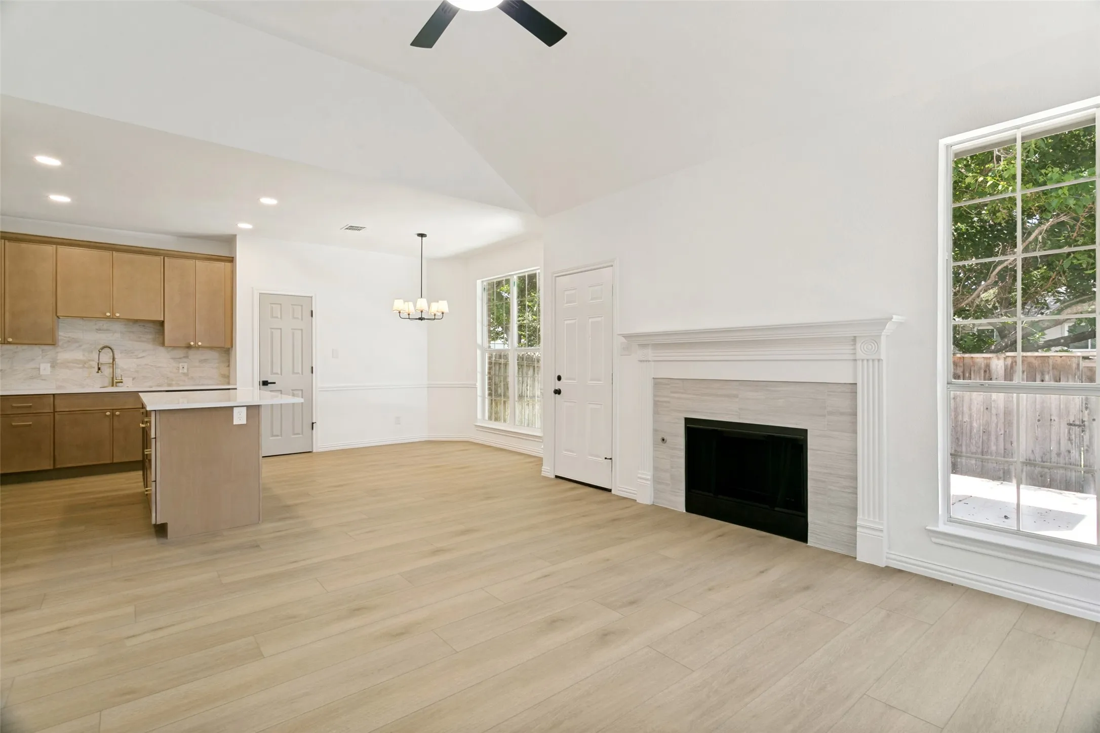 Spacious open-concept living area featuring light wood-finish flooring and a vaulted ceiling