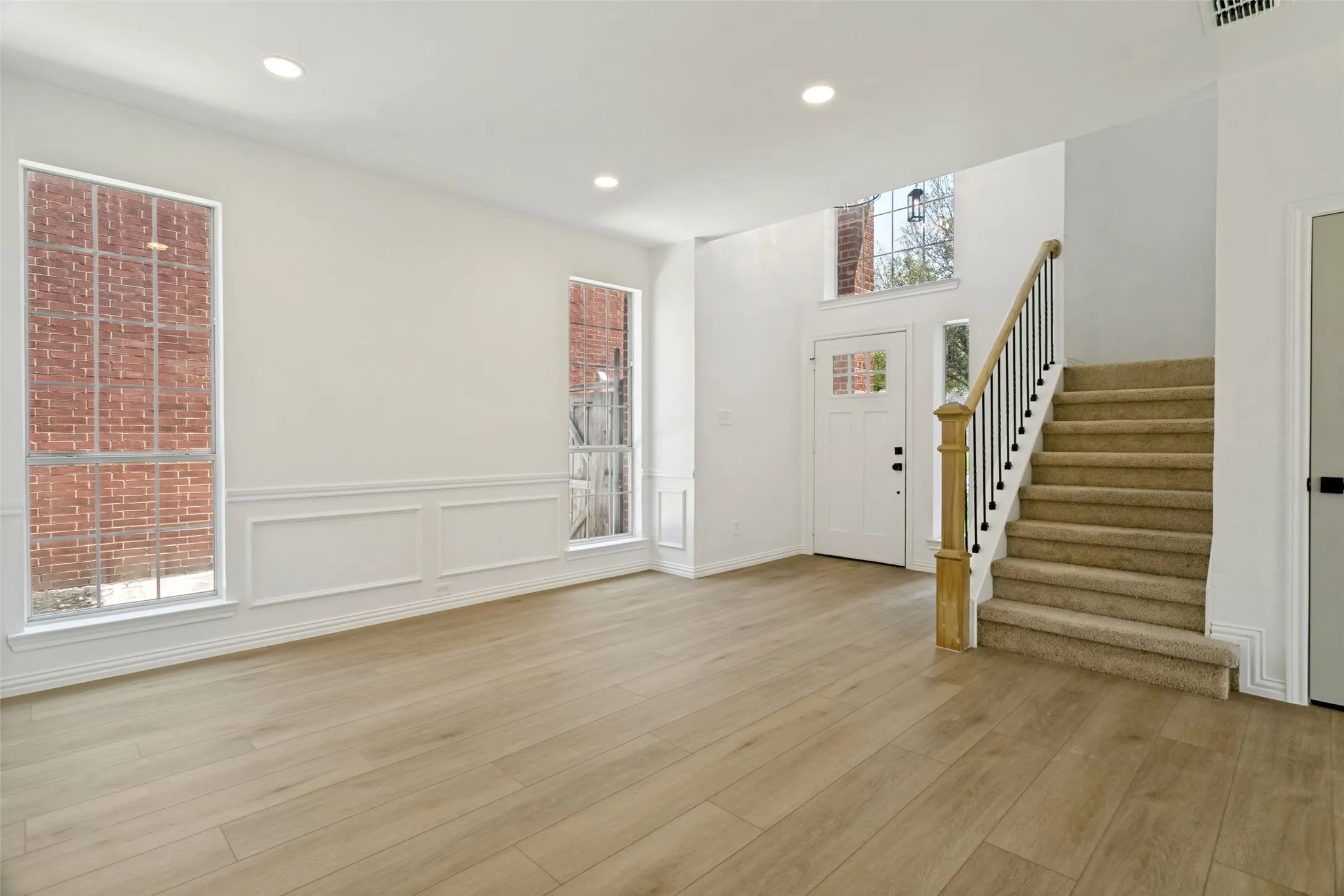 Entry foyer featuring a wood-finish floor and a carpeted staircase with wrought iron balusters