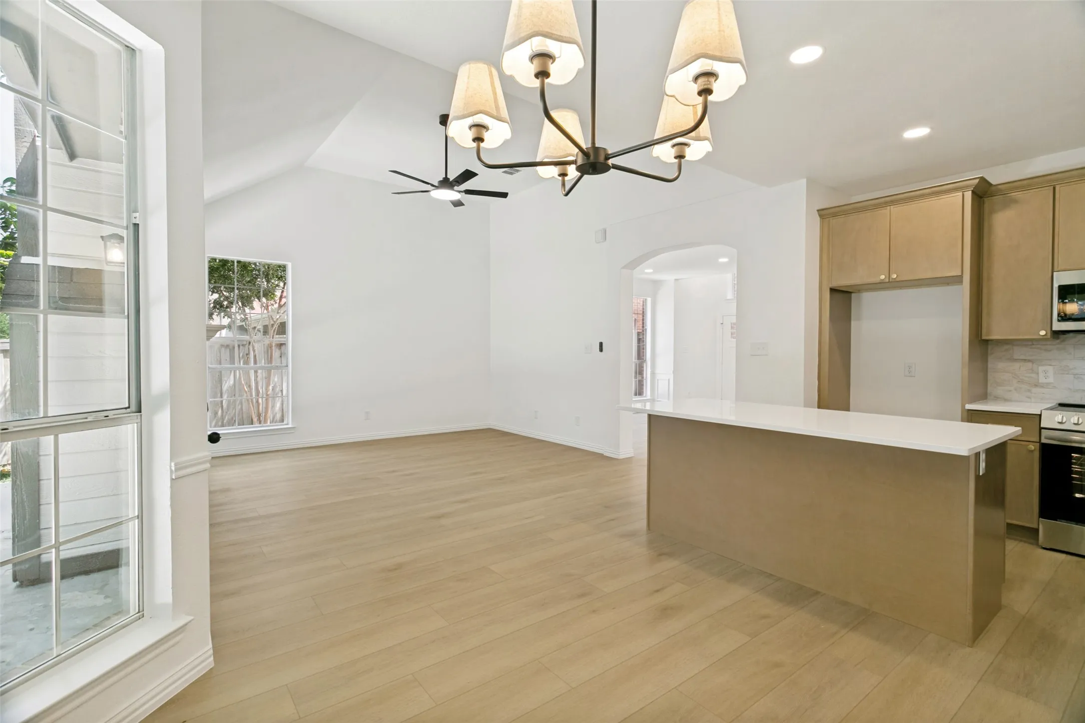 Open-concept living space featuring vaulted ceilings, wood-finish flooring, and ample natural light from multiple windows