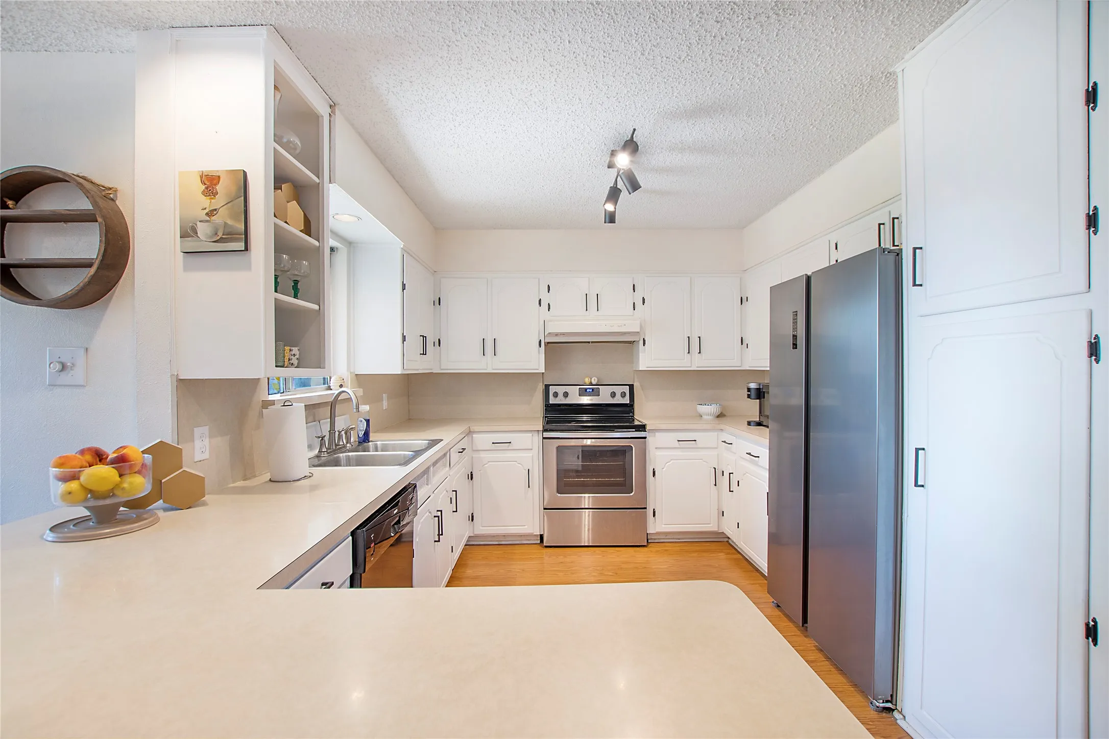 U-shaped kitchen featuring white cabinetry, light-toned countertops, and wood-finish flooring