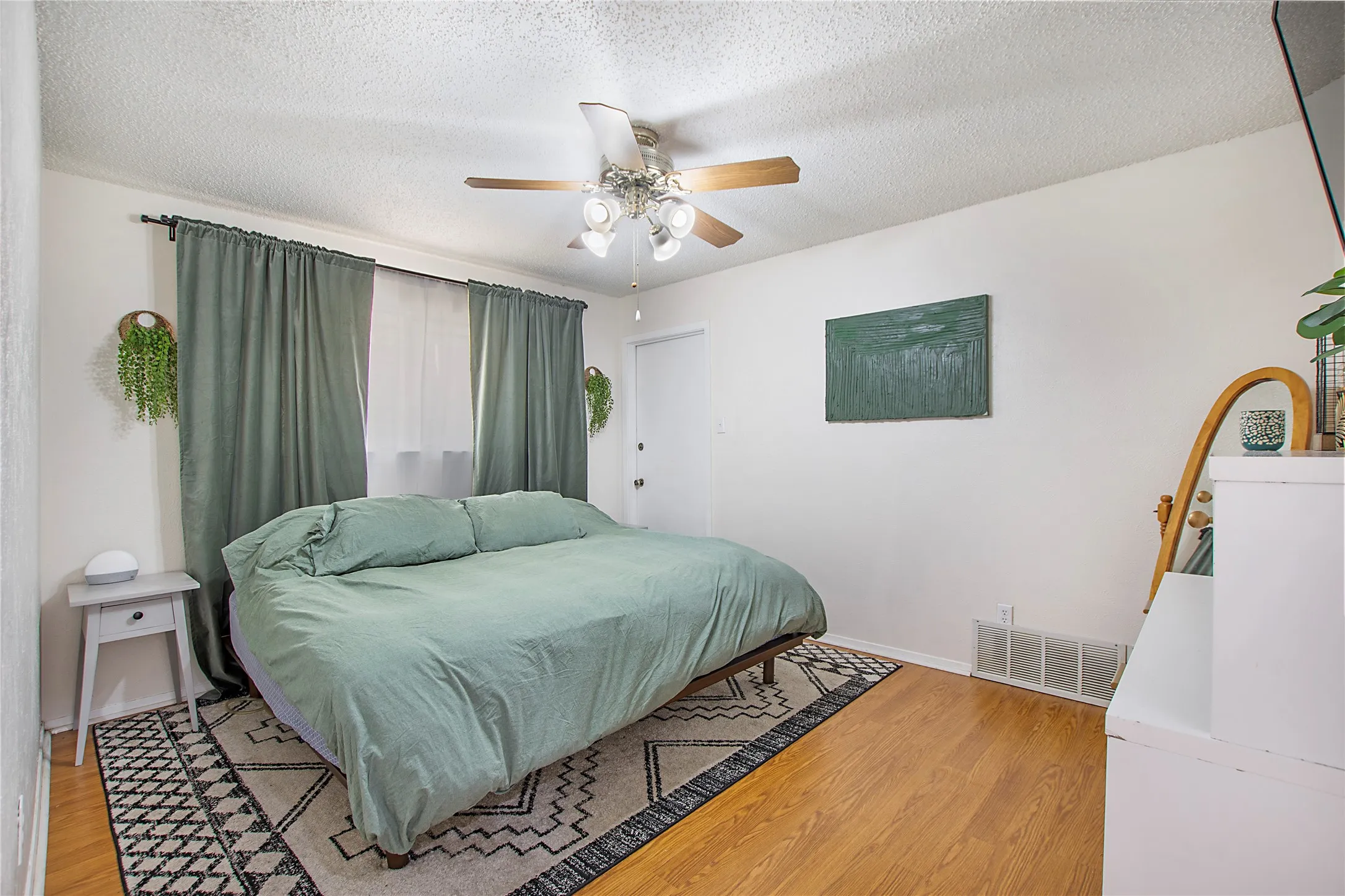 Bedroom featuring wood-finish flooring, a ceiling fan with integrated lighting, and a white door with a silver-tone handle