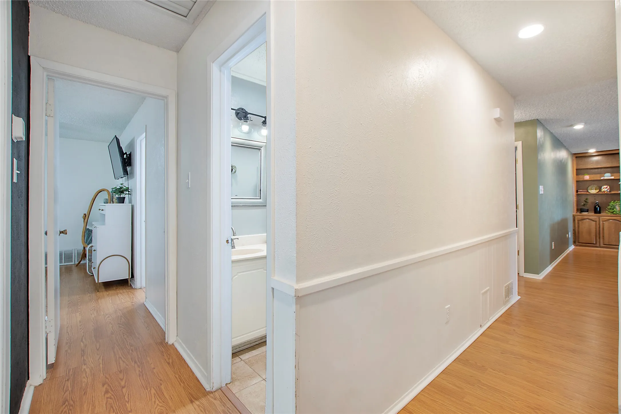 Hallway featuring wood-finish flooring, neutral paint, and white chair rail molding