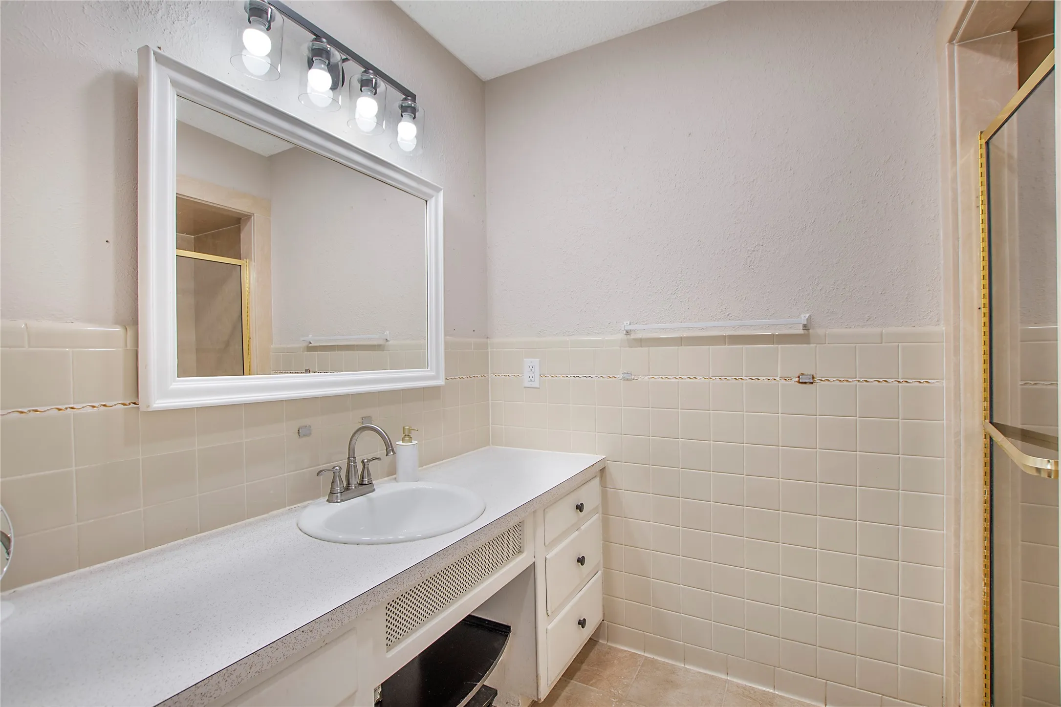 Bathroom vanity with an integrated sink, brushed nickel faucet, and a large framed mirror