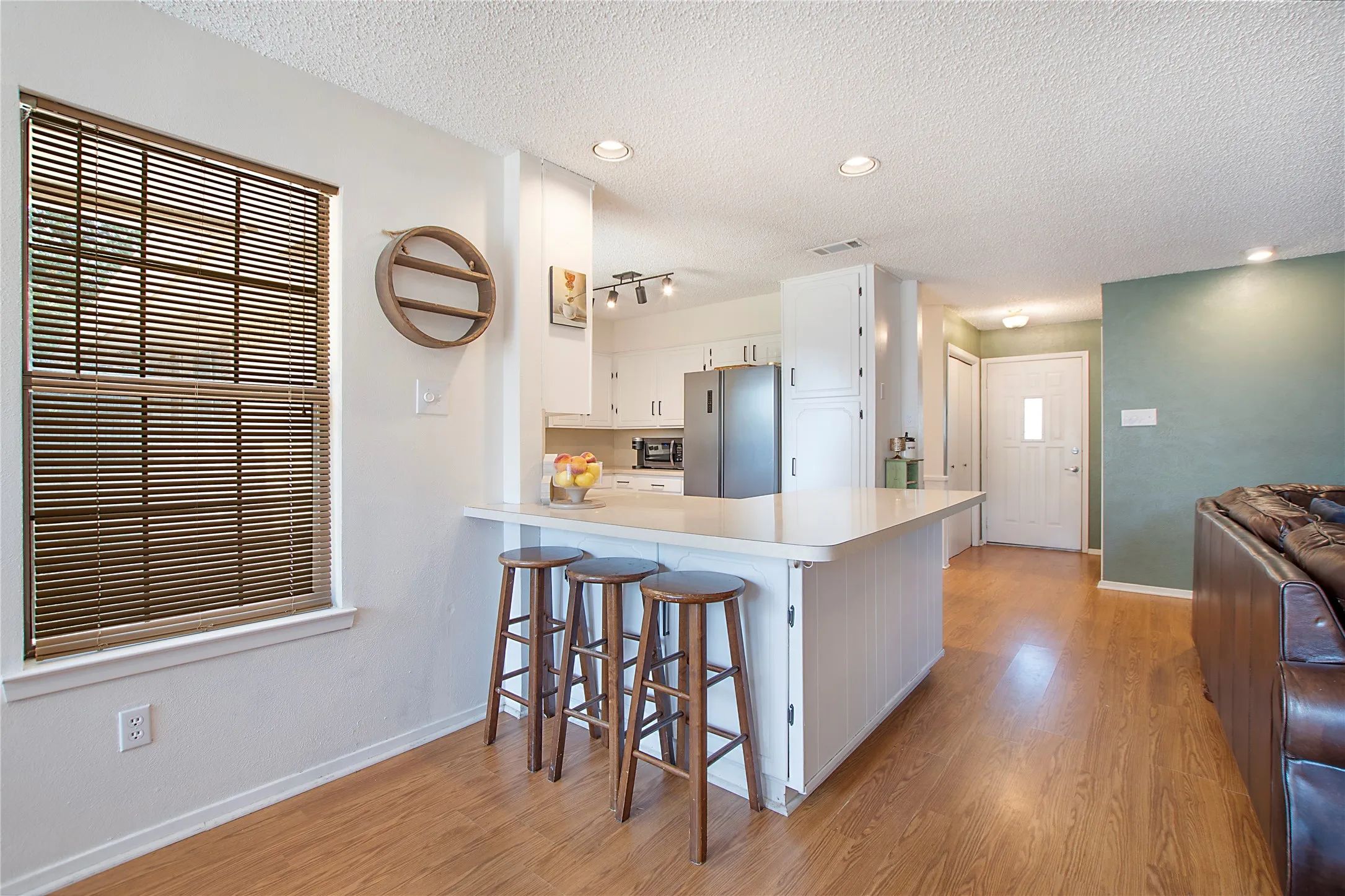 Kitchen featuring a breakfast bar with white paneling and a light-toned countertop, recessed lighting, and wood-finish flooring