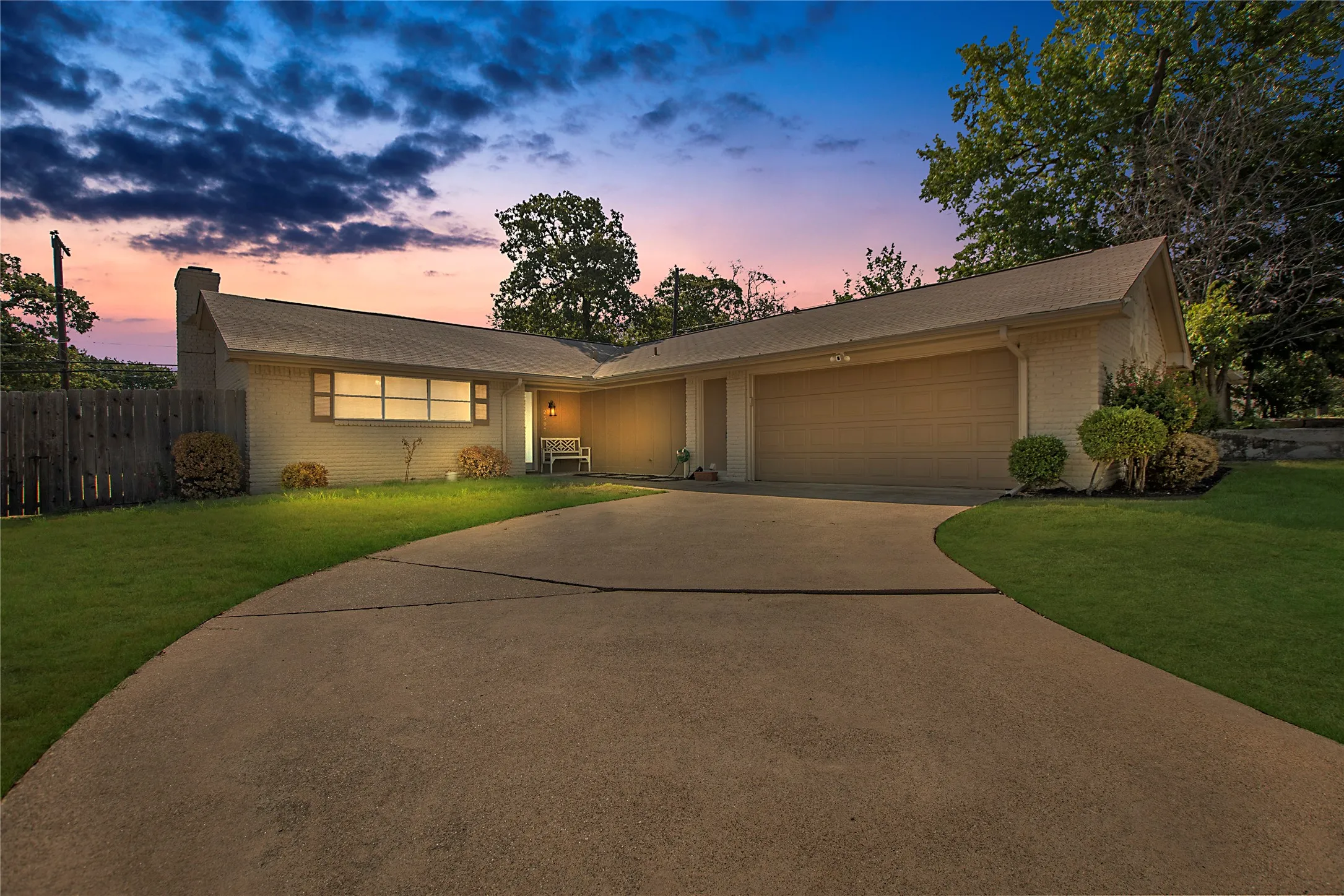 Single-story residence featuring light-colored brick siding, a two-car garage, and a concrete driveway