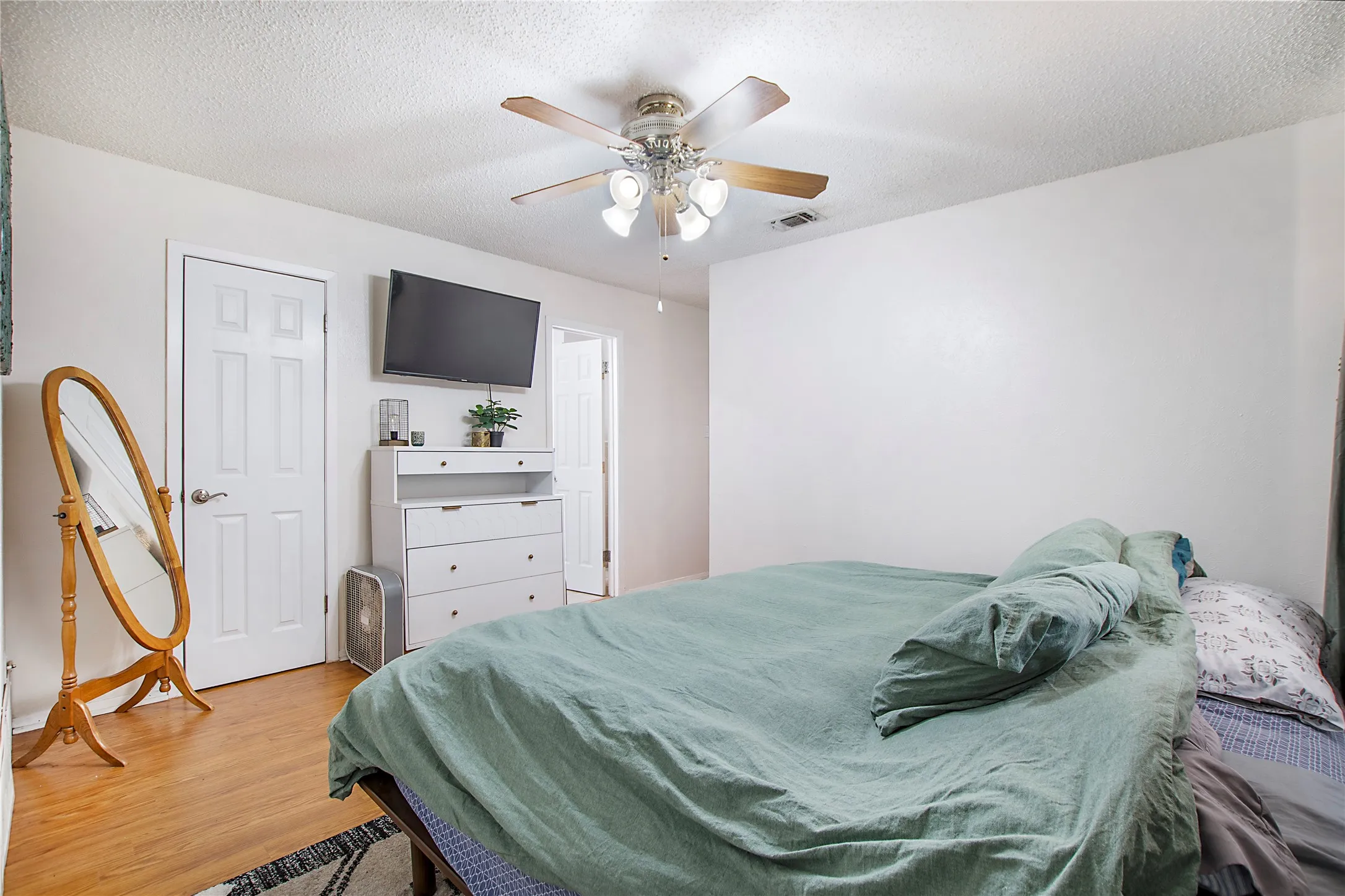 Room featuring wood-finish flooring, a ceiling fan with light fixture, and white painted walls