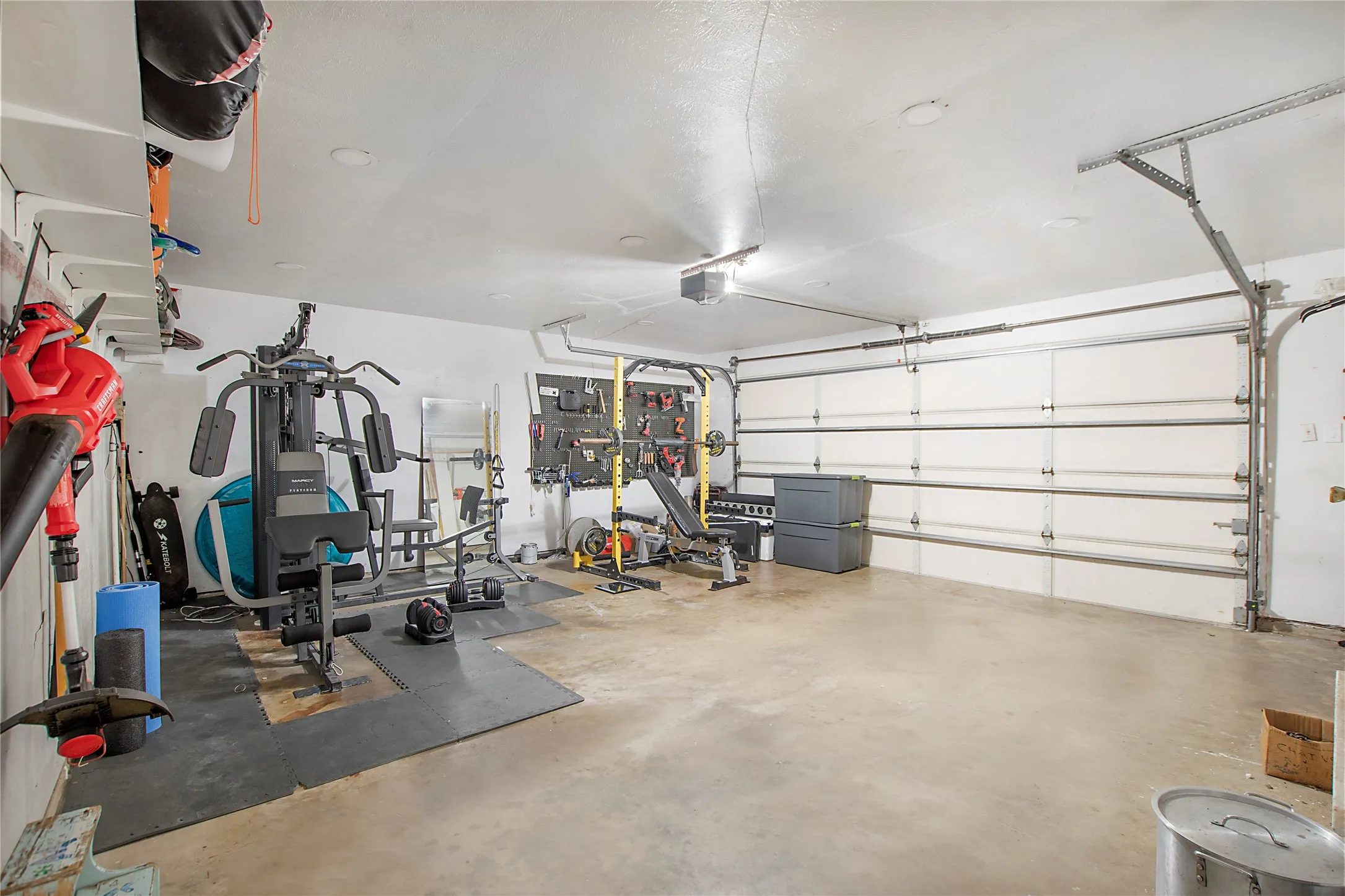Spacious garage featuring a concrete floor, bright overhead lighting, and white walls