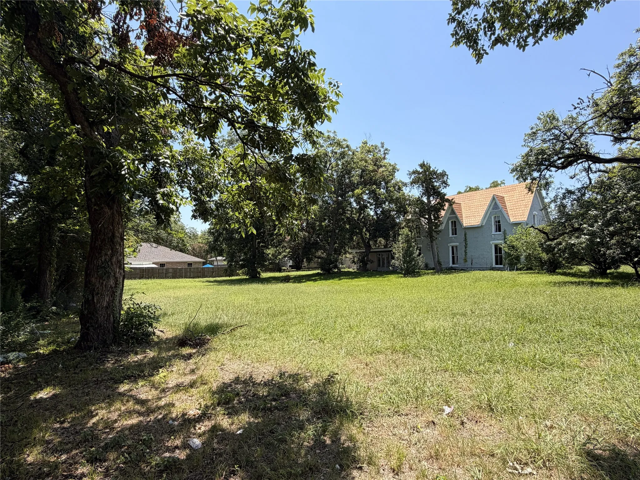 Expansive green lawn with mature trees bordering the property