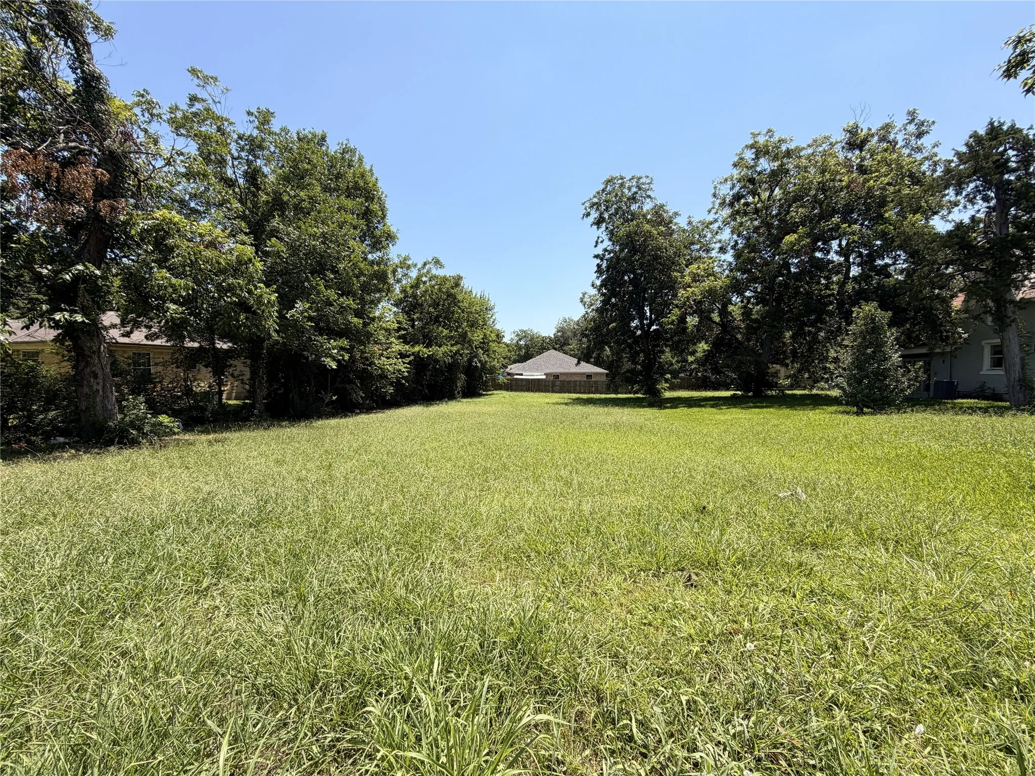 Expansive grass lot bordered by mature trees