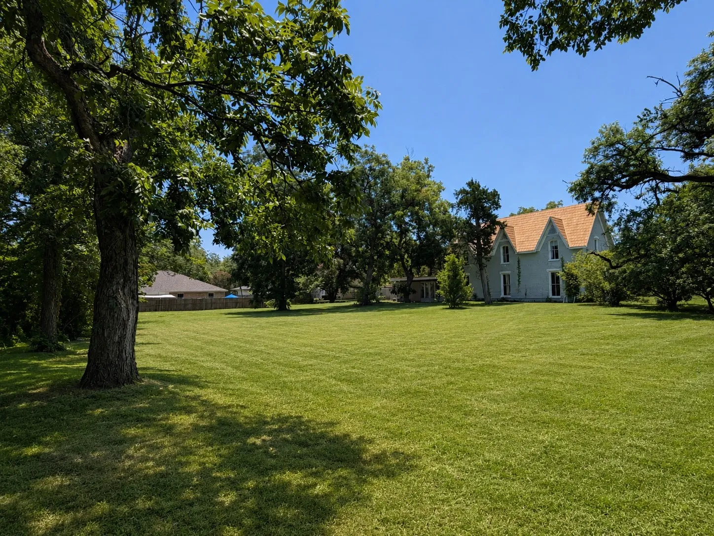 Expansive green lawn surrounding a light blue residence with a gabled roof