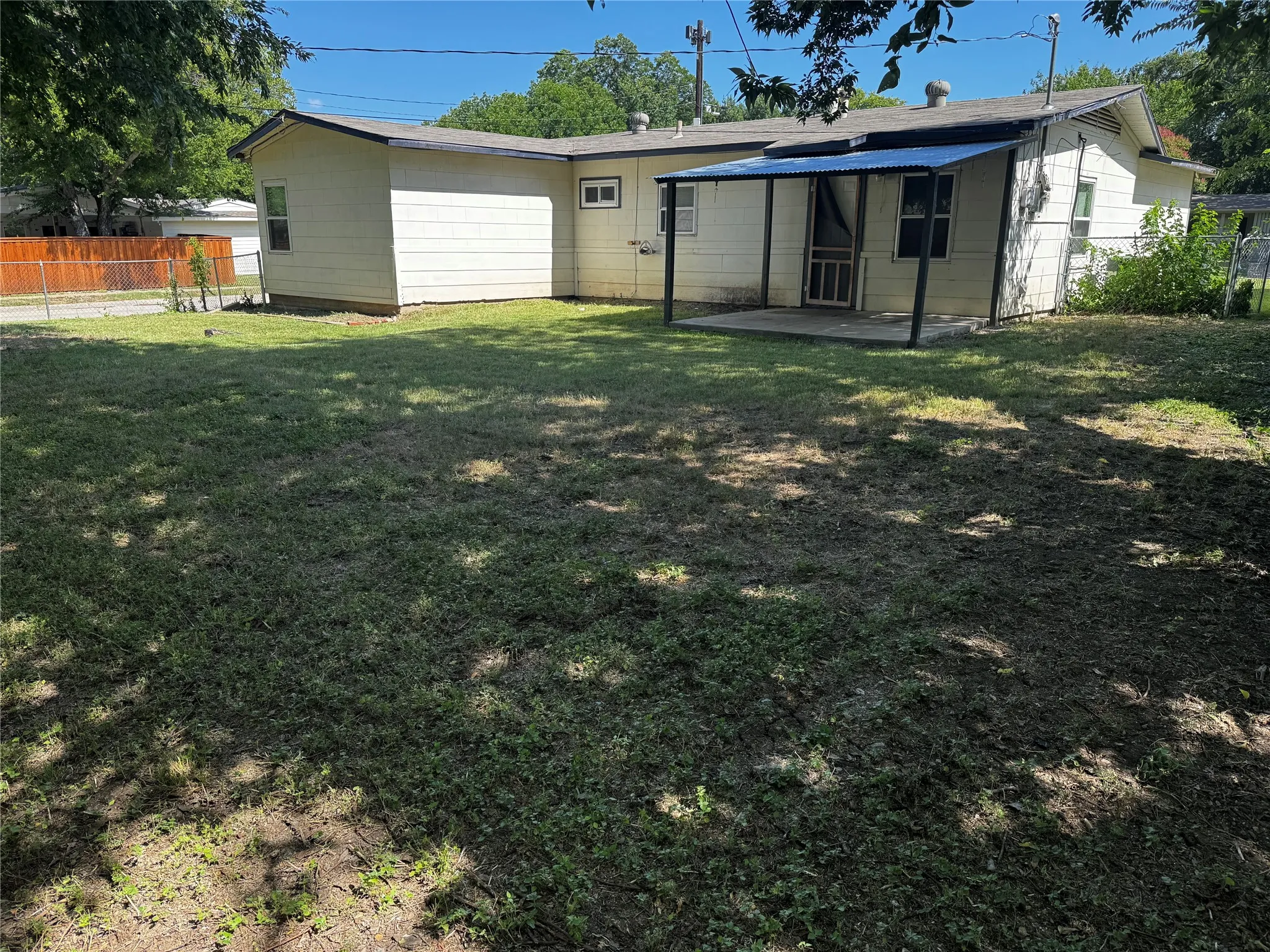 Expansive rear yard featuring a covered patio, a privacy fence, and mature trees