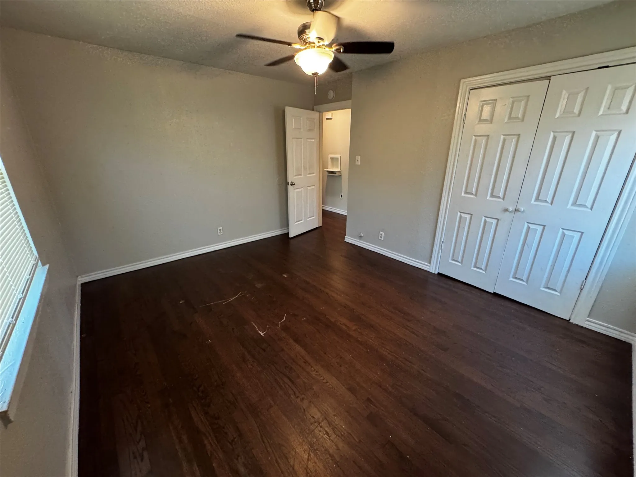 Bedroom featuring dark wood-finish flooring, light neutral-toned walls, and white baseboards