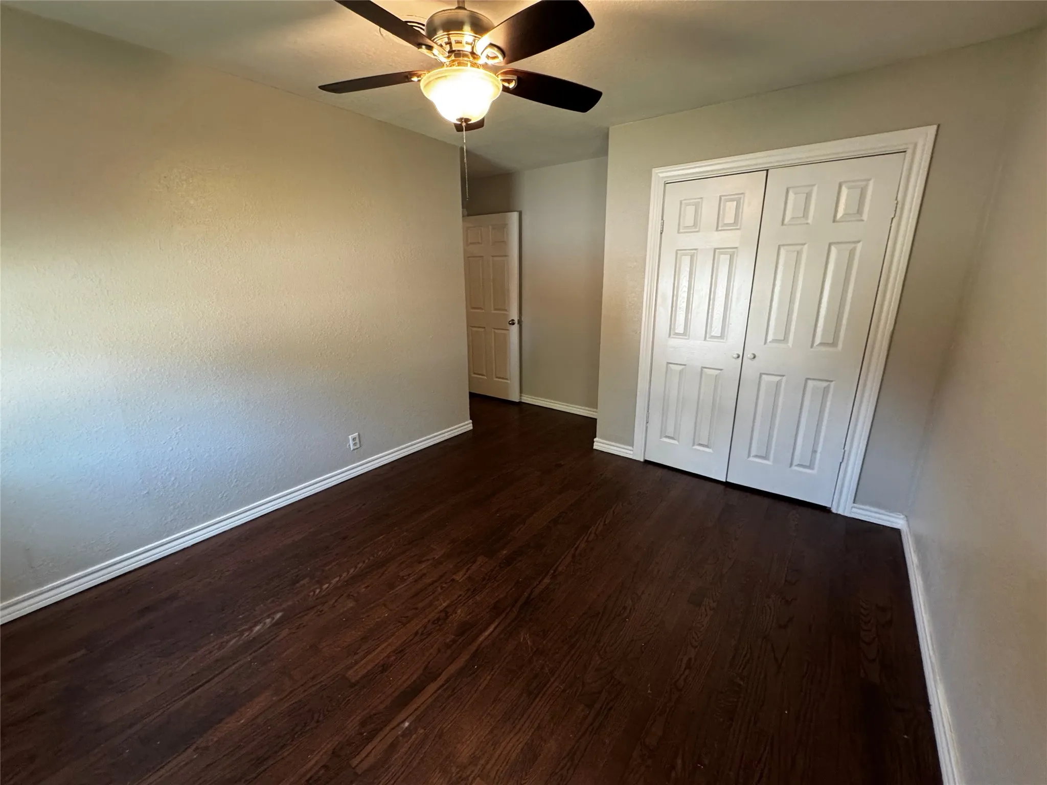 Room featuring wood-finish flooring, light-toned walls, and white baseboards