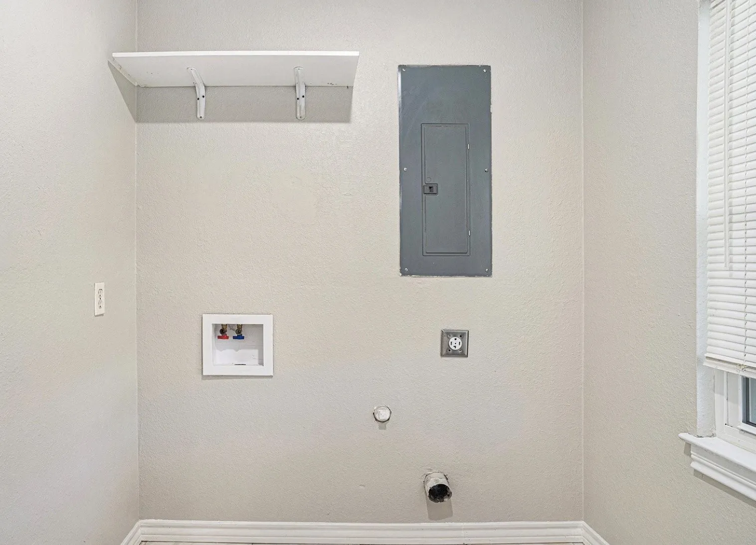 Laundry area featuring a utility shelf, electrical panel, and hookups for appliances