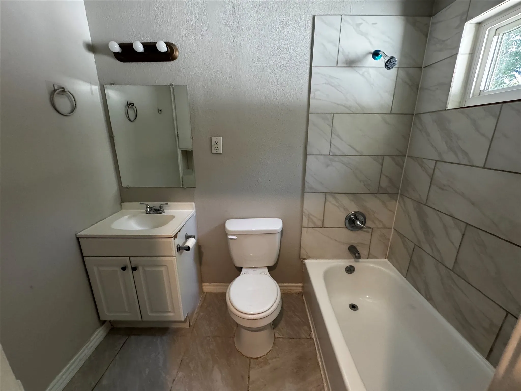 Bathroom featuring a built-in bathtub with subway tile surround, a window, and a vanity with an integrated sink