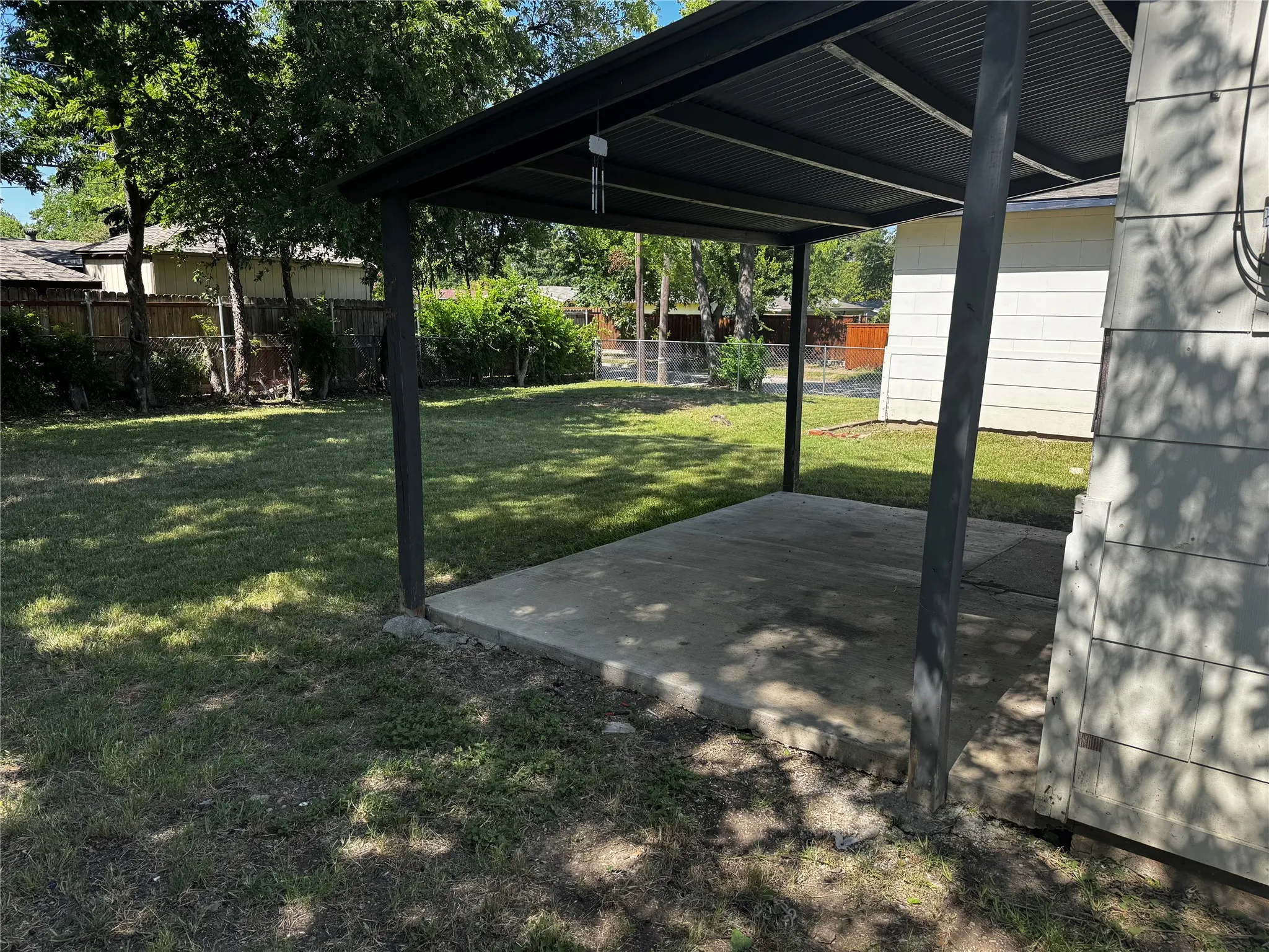 Covered patio with a concrete slab, corrugated metal roof, and metal support posts
