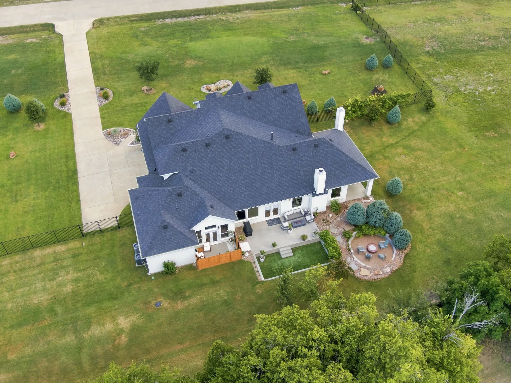 Expansive property featuring a white exterior, dark shingle roofing, and multiple chimneys