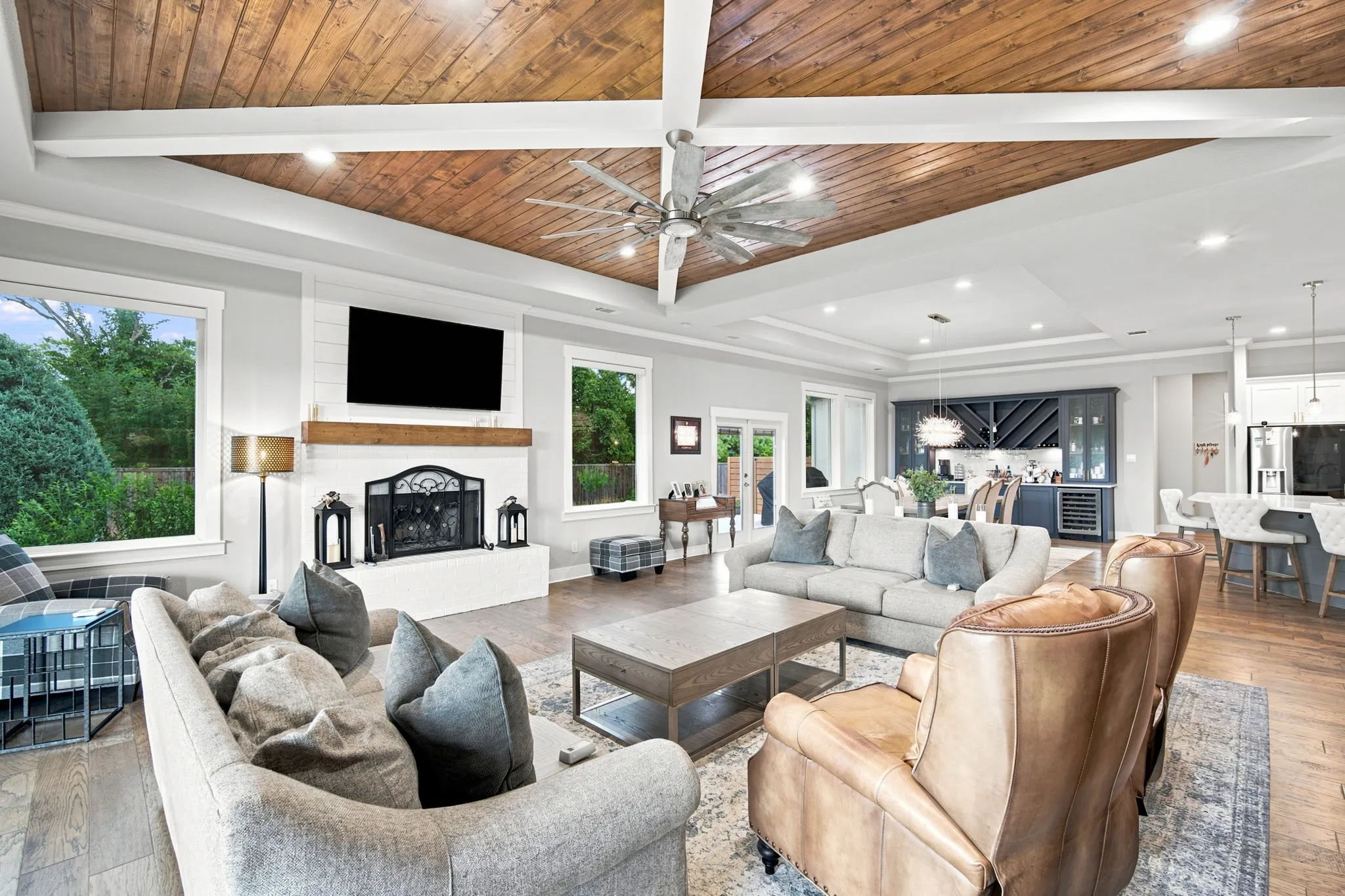 Living area featuring a vaulted wood-plank ceiling with exposed beams, a white brick fireplace with a wood mantel, and wood-finish flooring
