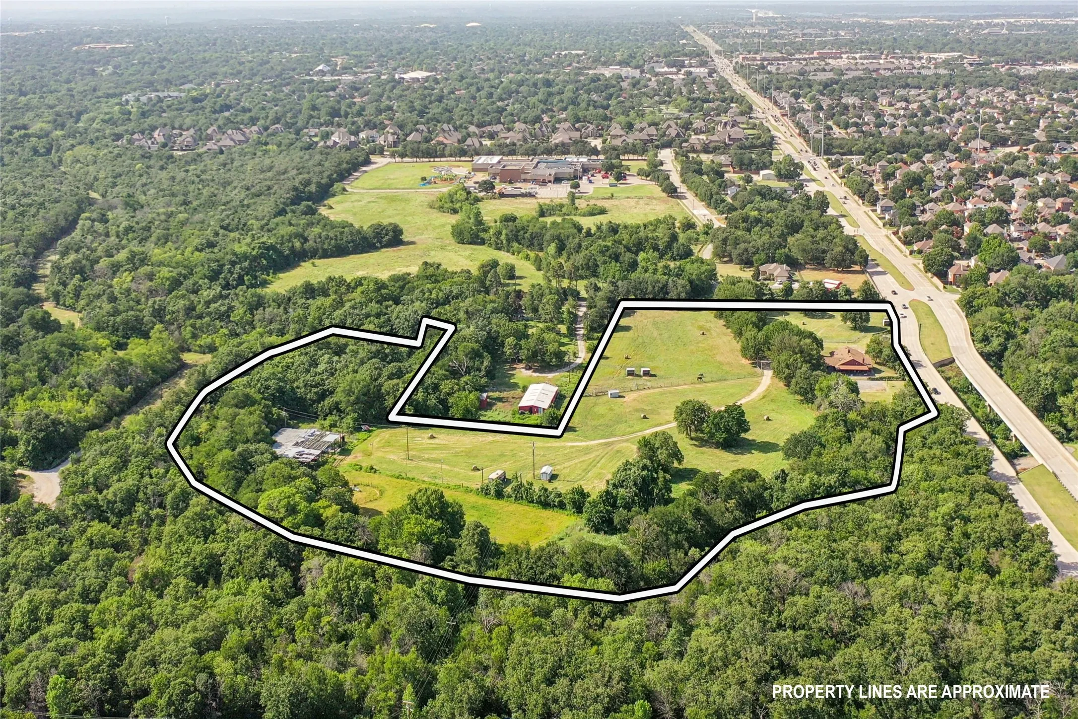 Expansive aerial view showcasing a large land parcel with mature trees and open grassy areas