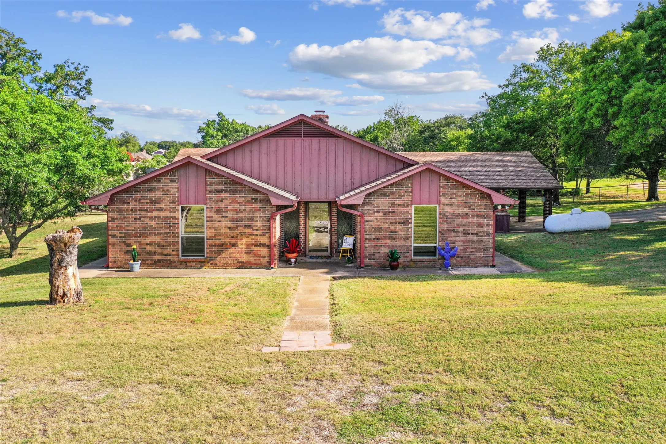 Brick exterior with vertical siding accents, a covered entry, and a covered carport structure