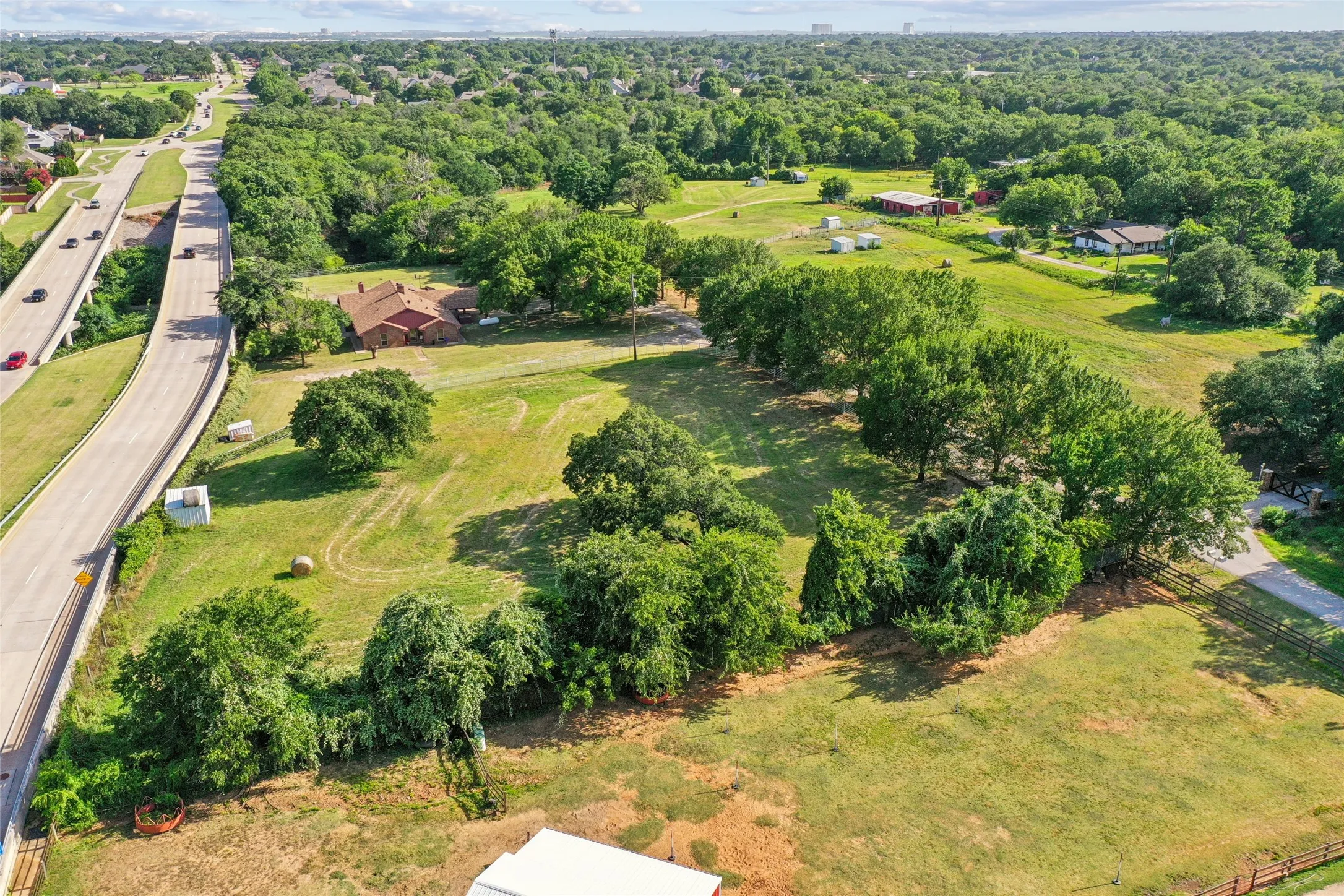 Expansive parcel featuring a substantial tree line, multiple structures, and varied topography