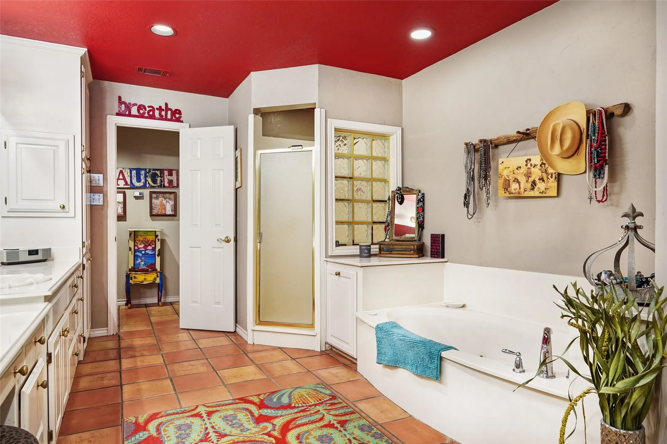 Bathroom featuring a built-in soaking tub, corner shower with glass block window, and tile flooring