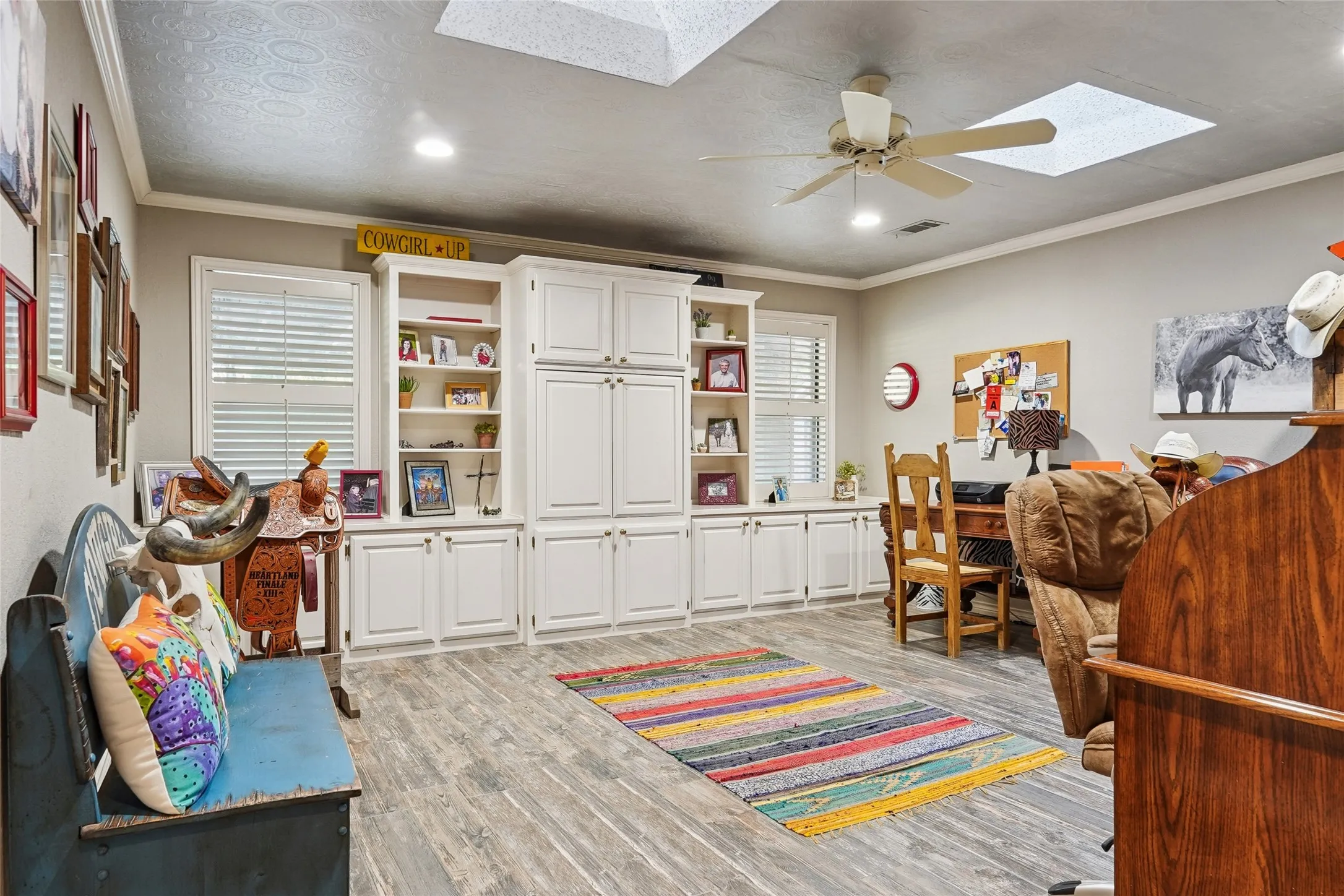 Spacious interior featuring wood-finish flooring, white built-in cabinetry with open shelving, recessed lighting, and a ceiling fan