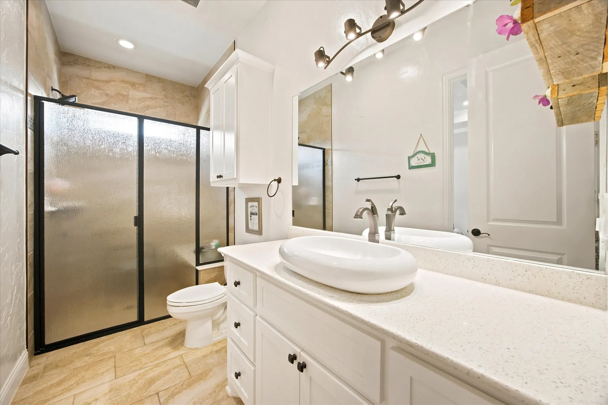 Bathroom featuring a white vanity with an undermount vessel sink, a light-toned countertop, and white cabinetry
