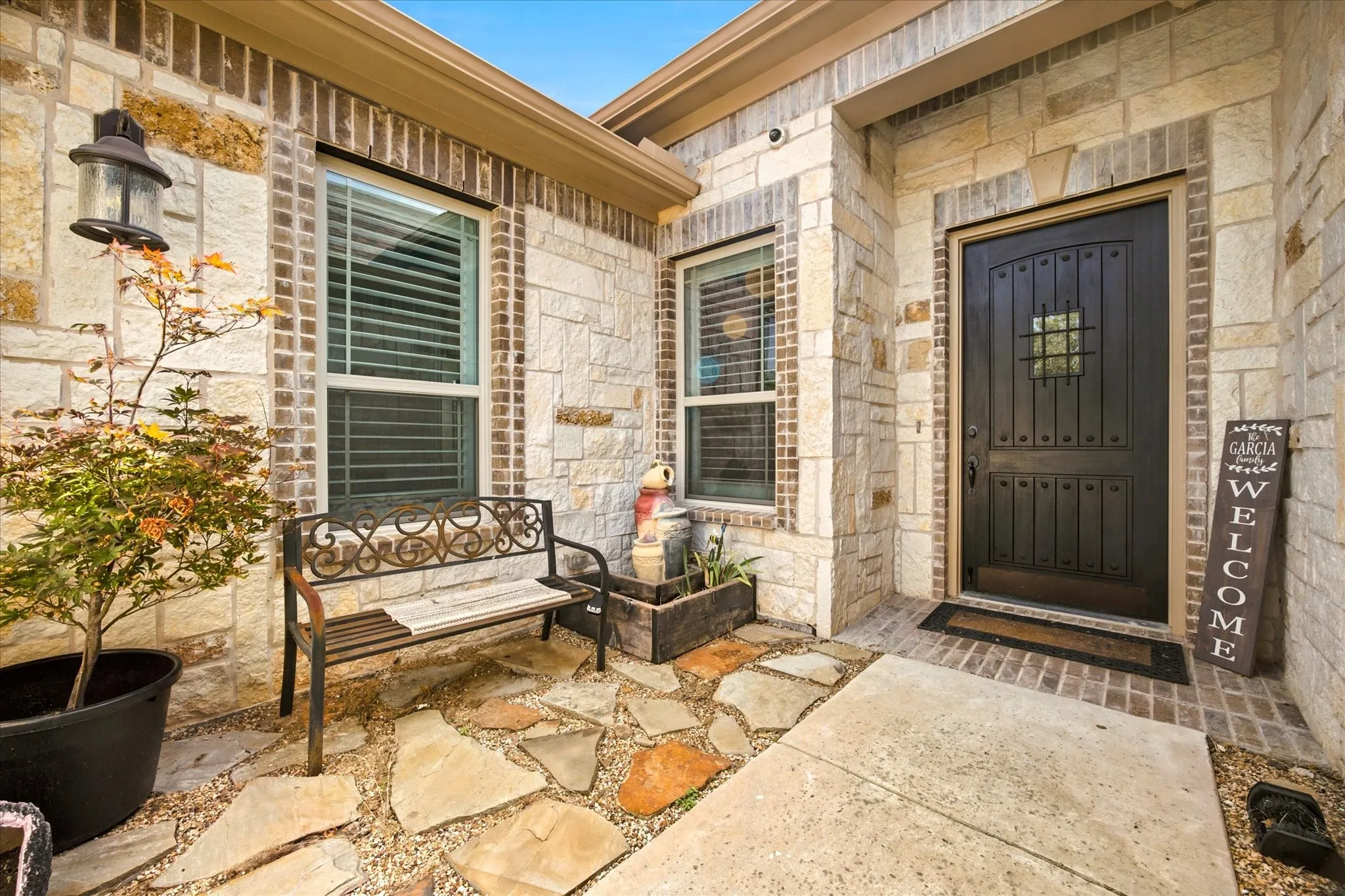 Stone and brick facade with a dark wood-finish entry door featuring an iron grille