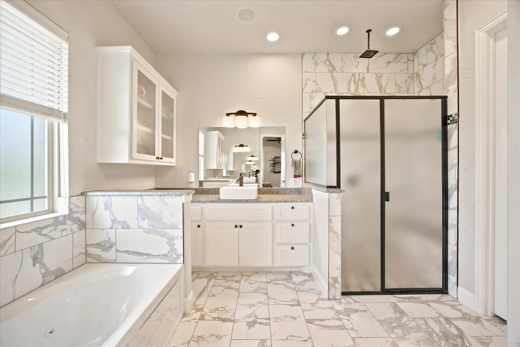 Spacious bathroom featuring marble-look tile flooring and wainscoting
