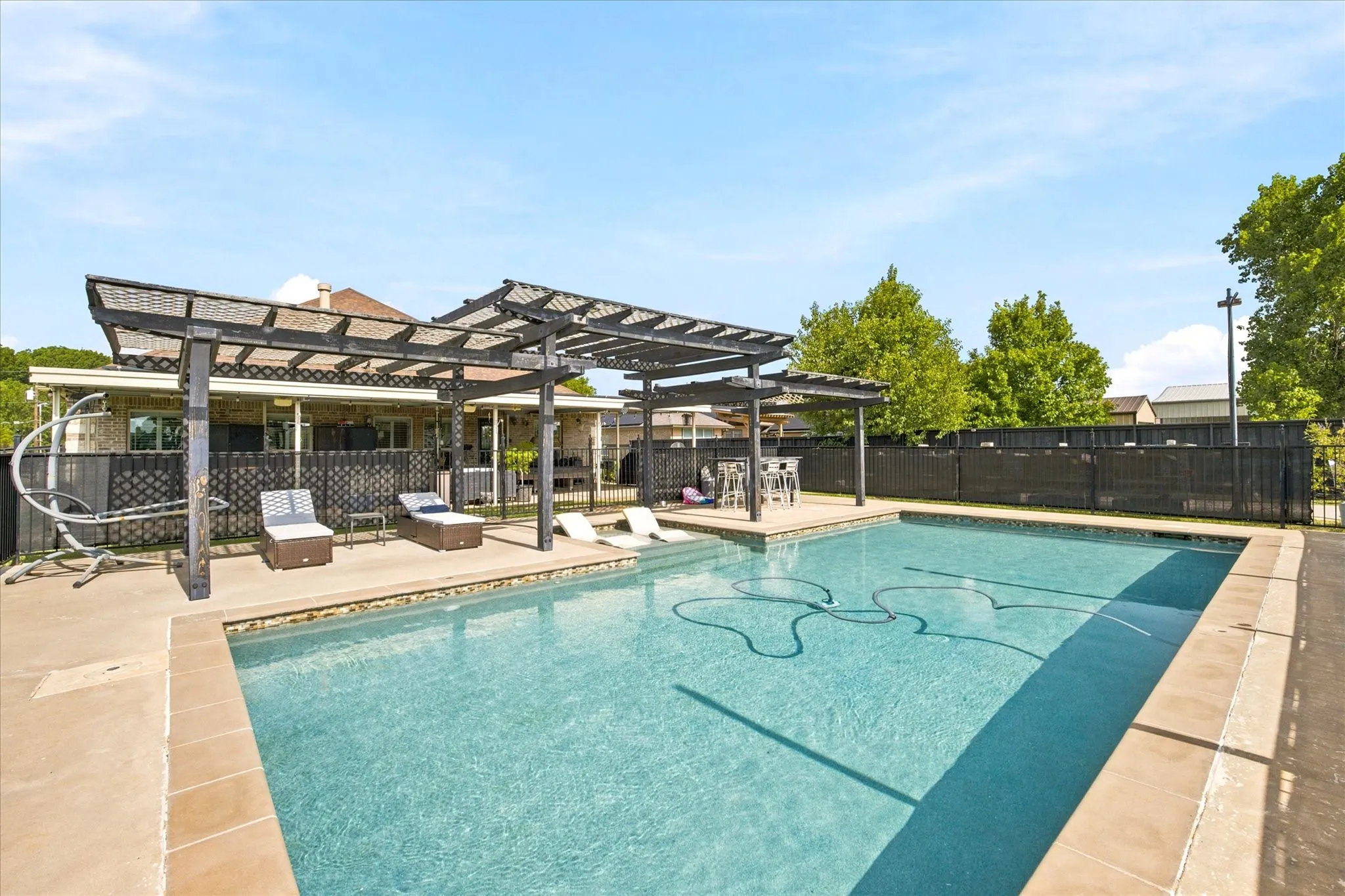 Outdoor swimming pool with concrete decking and perimeter fencing
