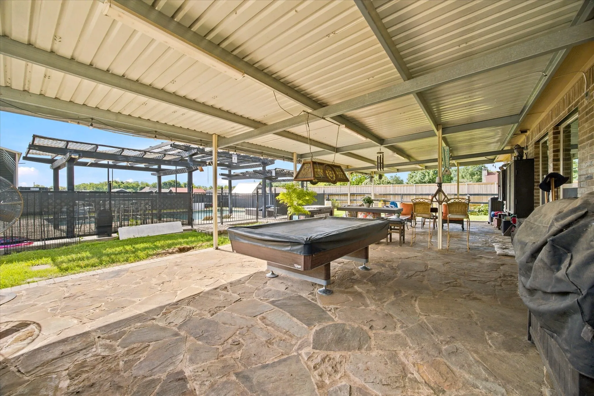 Expansive covered patio featuring flagstone flooring, a large overhead awning, and direct access to an enclosed outdoor area