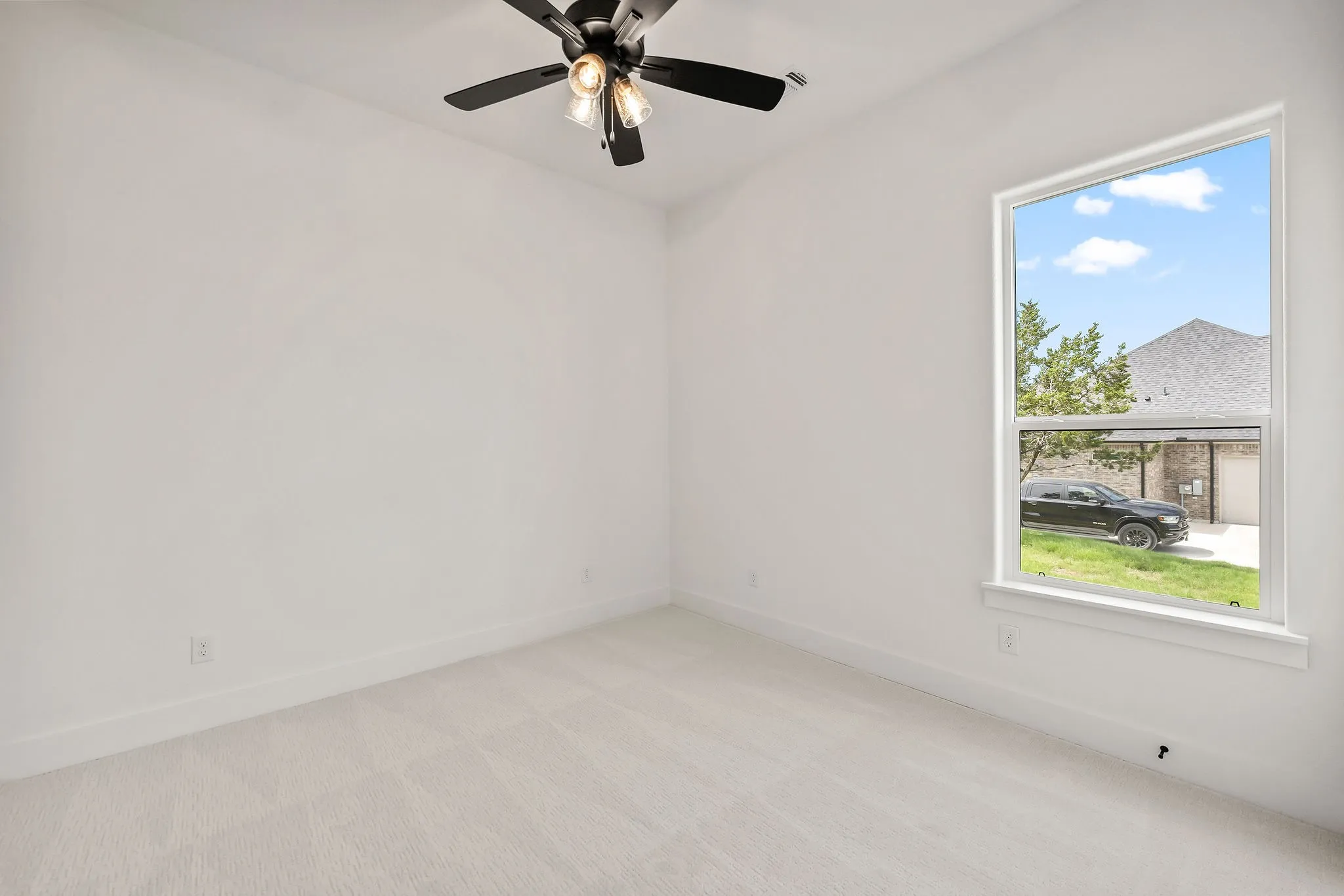 Spacious room featuring neutral carpeting and a ceiling fan with integrated lighting