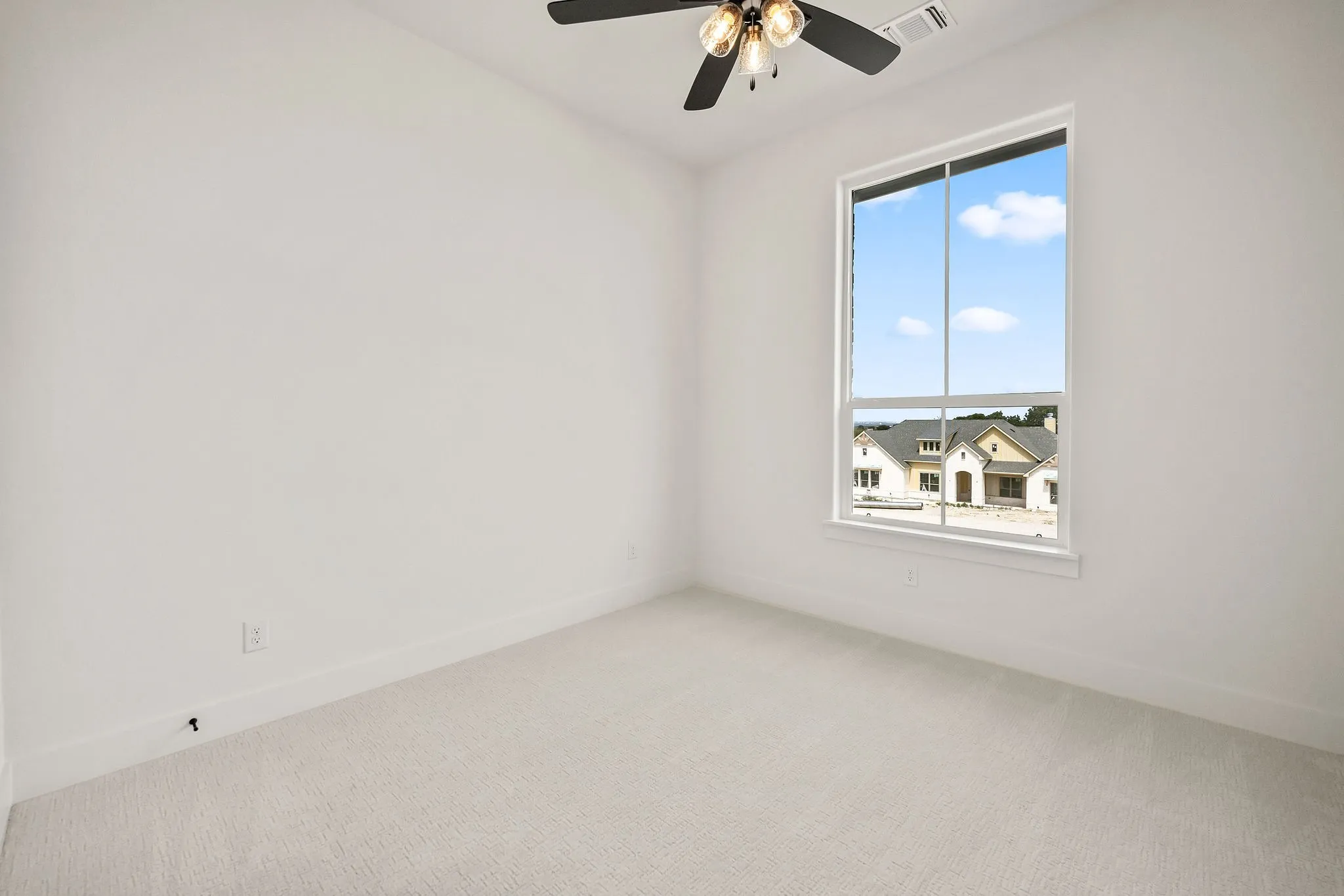 Bright room featuring a large window, neutral carpeting, white walls, and a ceiling fan with integrated lighting